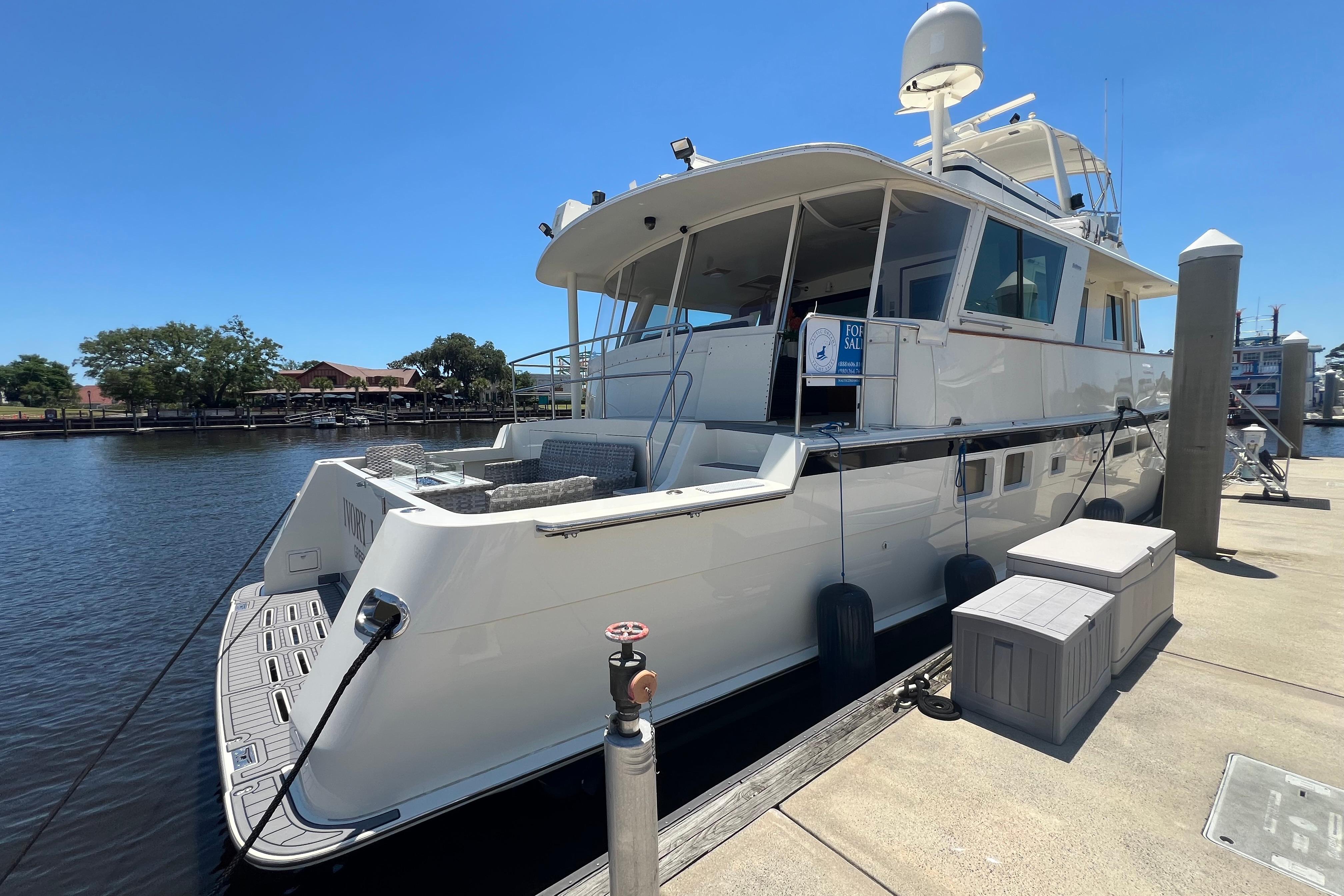 1987 Hatteras 70 Cockpit Motor Yacht docked, sunny day, for sale sign visible.