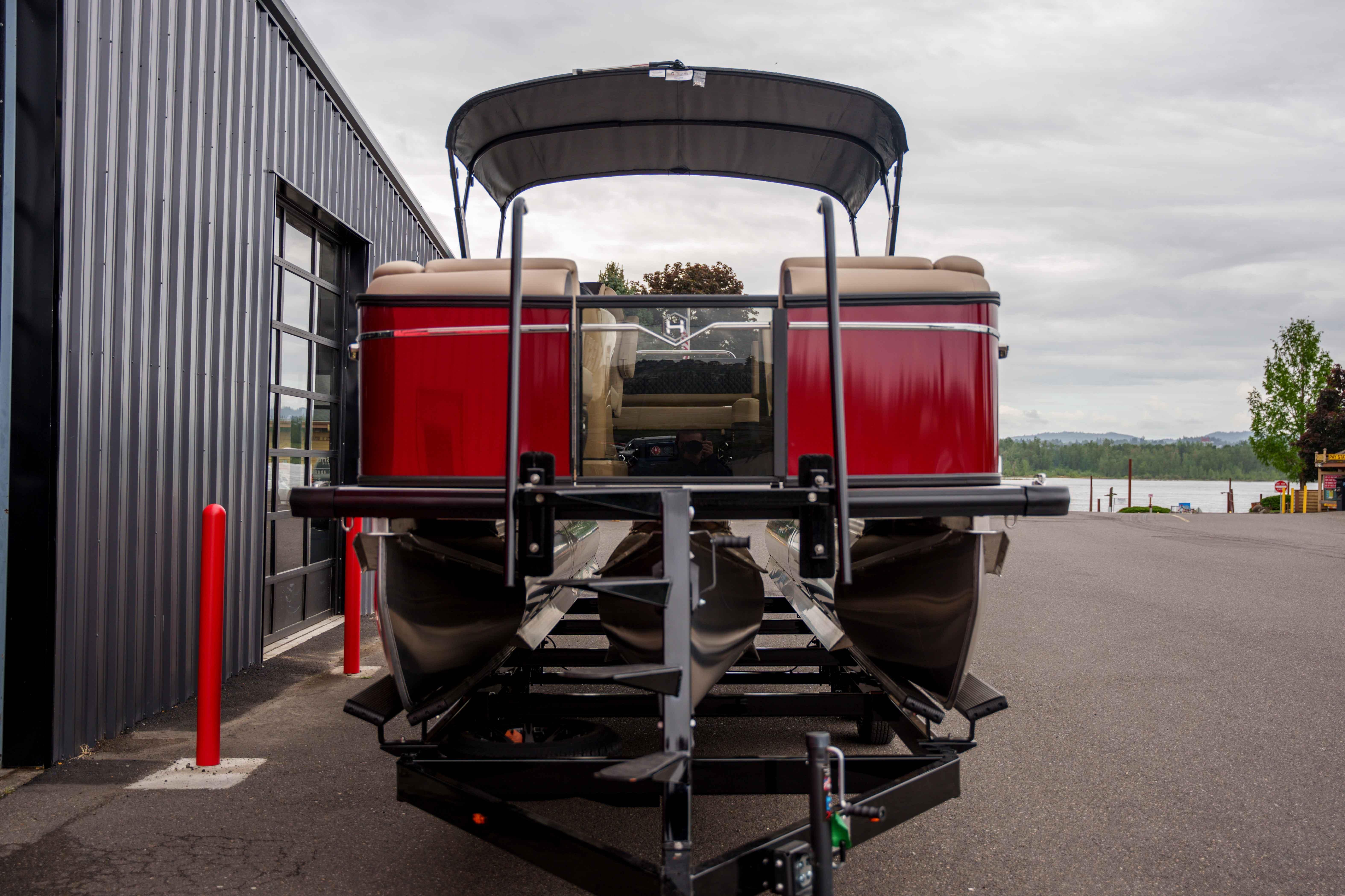 2026 Harris Sunliner 230 pontoon boat on trailer, parked near a modern building.