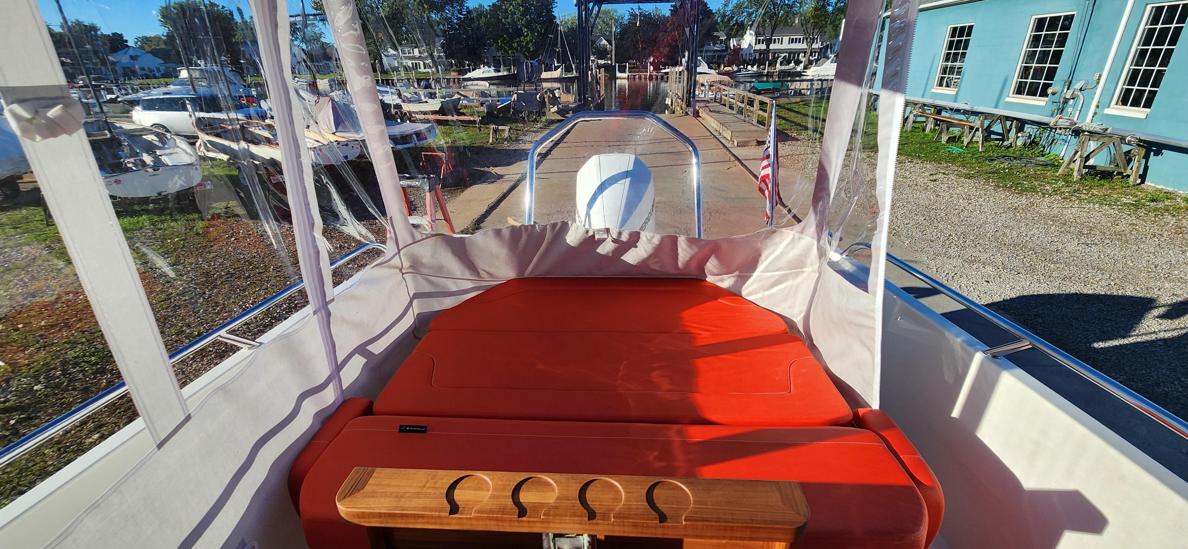 2023 Nimbus T8 boat interior with red seating and clear canopy, docked at a marina.