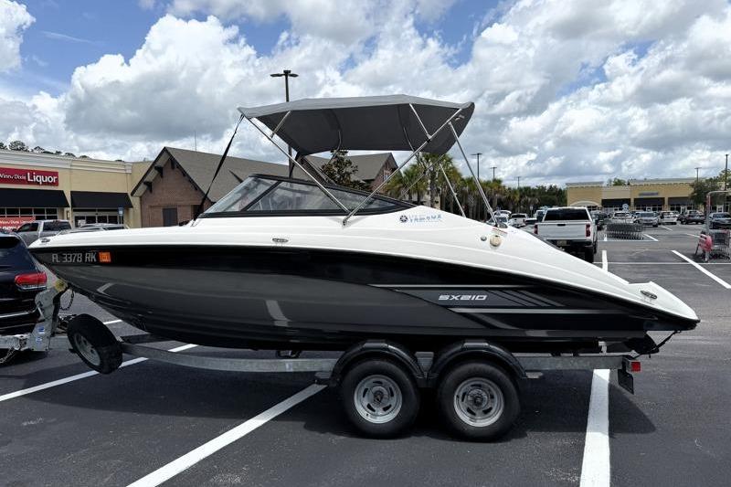 2017 Yamaha Boats SX210 on trailer in parking lot under cloudy sky.