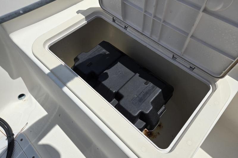 Open storage compartment on a 2000 May-Craft 2000CC boat, featuring a black battery box.