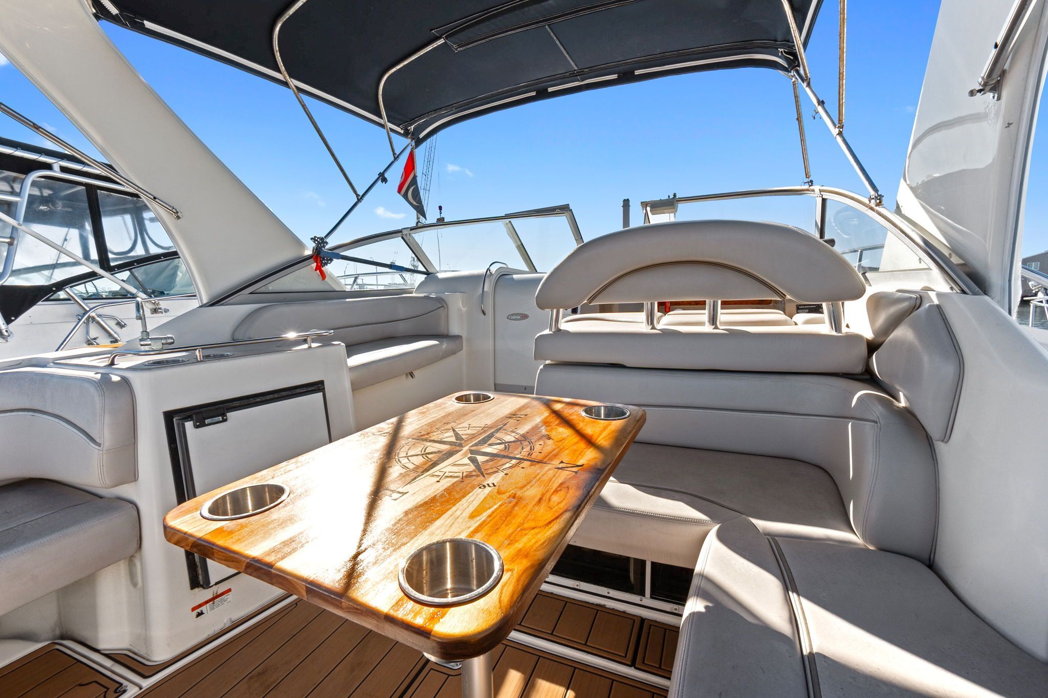 The image shows the cockpit of a 2007 Larson Cabrio 330 with a wooden table and cushioned seating.