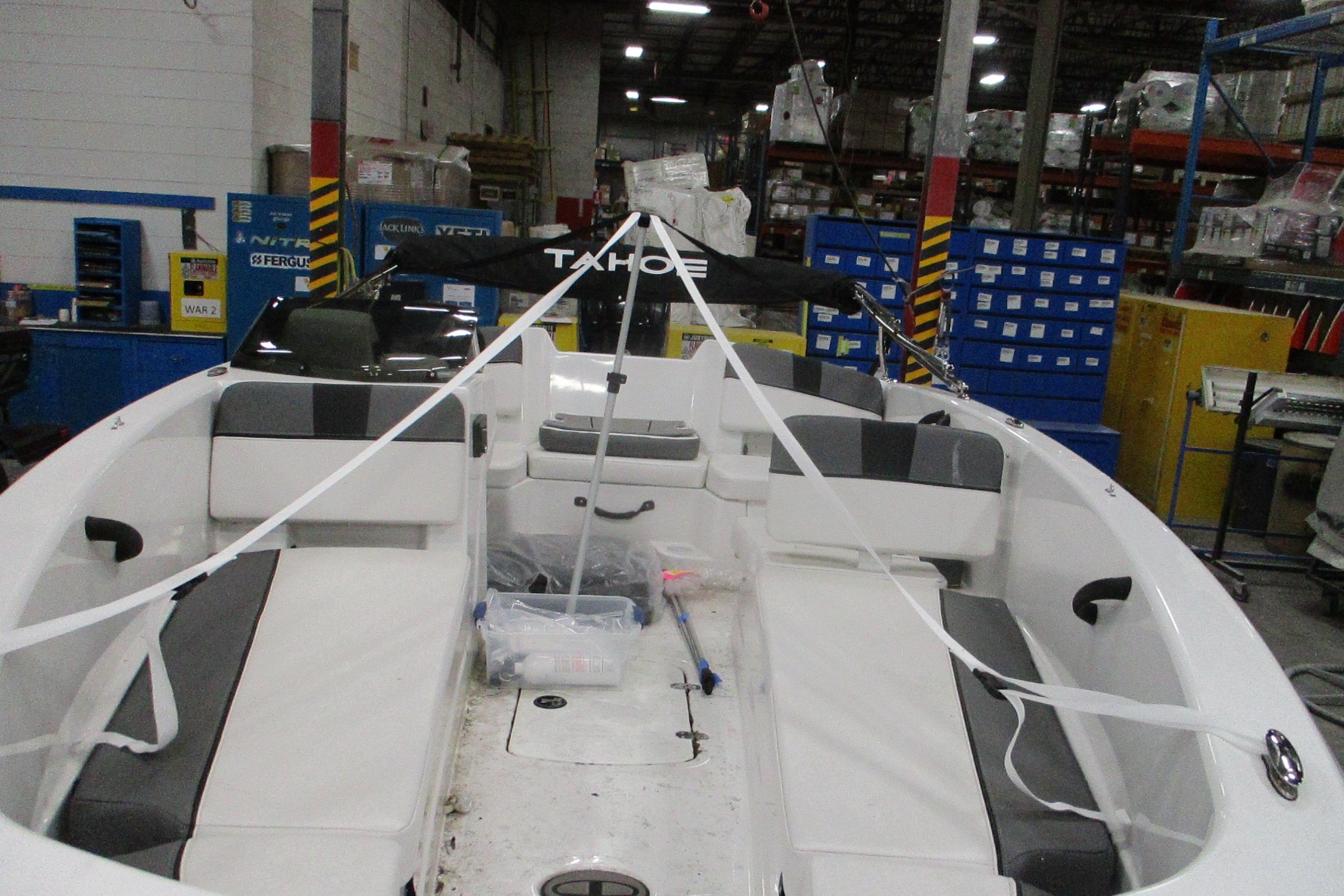 2025 Tahoe T18 boat interior in a warehouse setting, showcasing seating and storage.