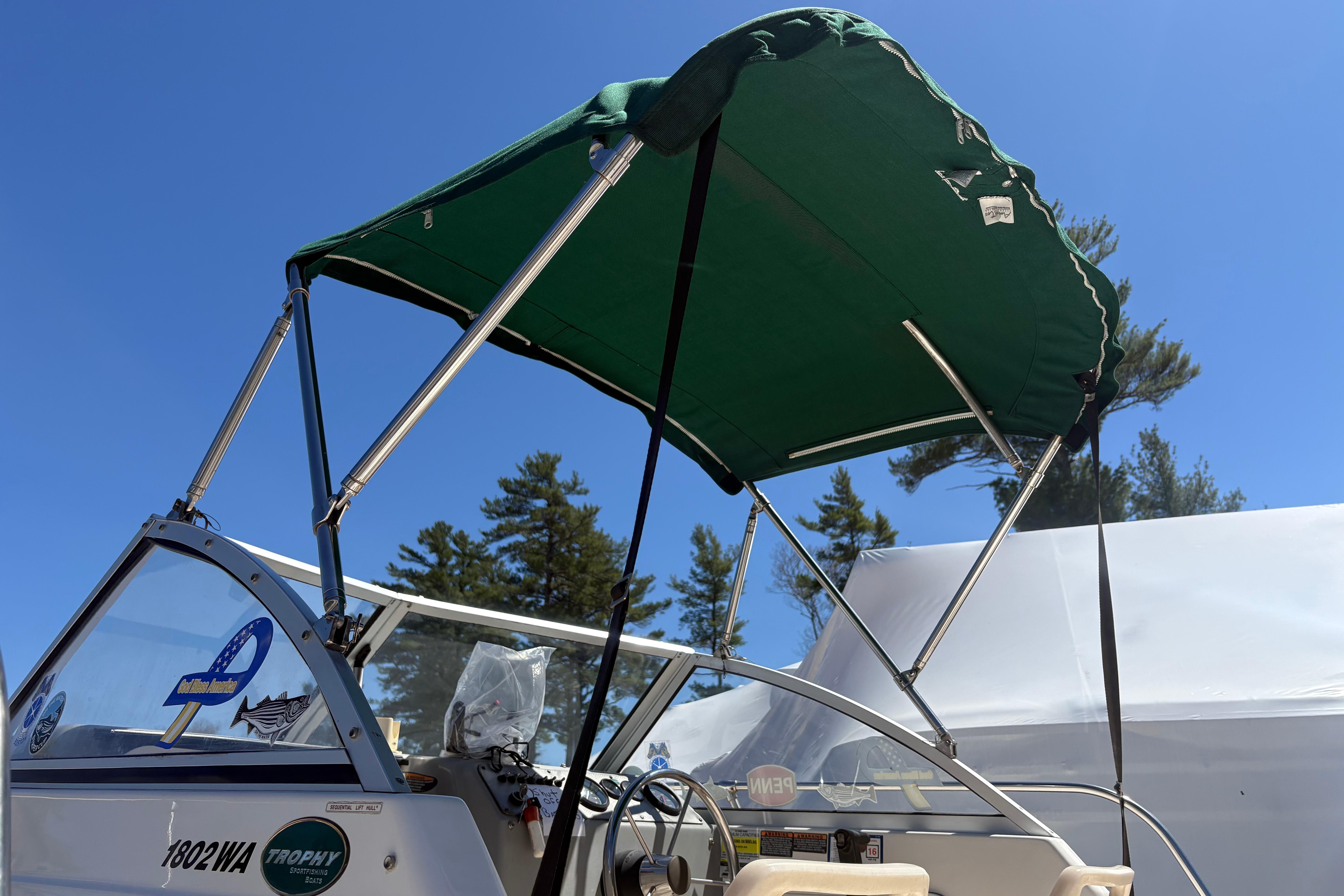 2004 Trophy 1802 Walkaround boat with green canopy under clear blue sky.