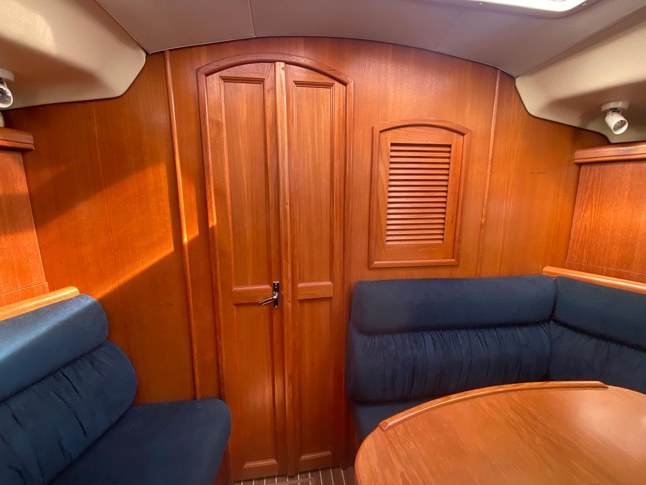 Interior of a 2003 Hunter 356 sailboat with wooden paneling and blue seating.