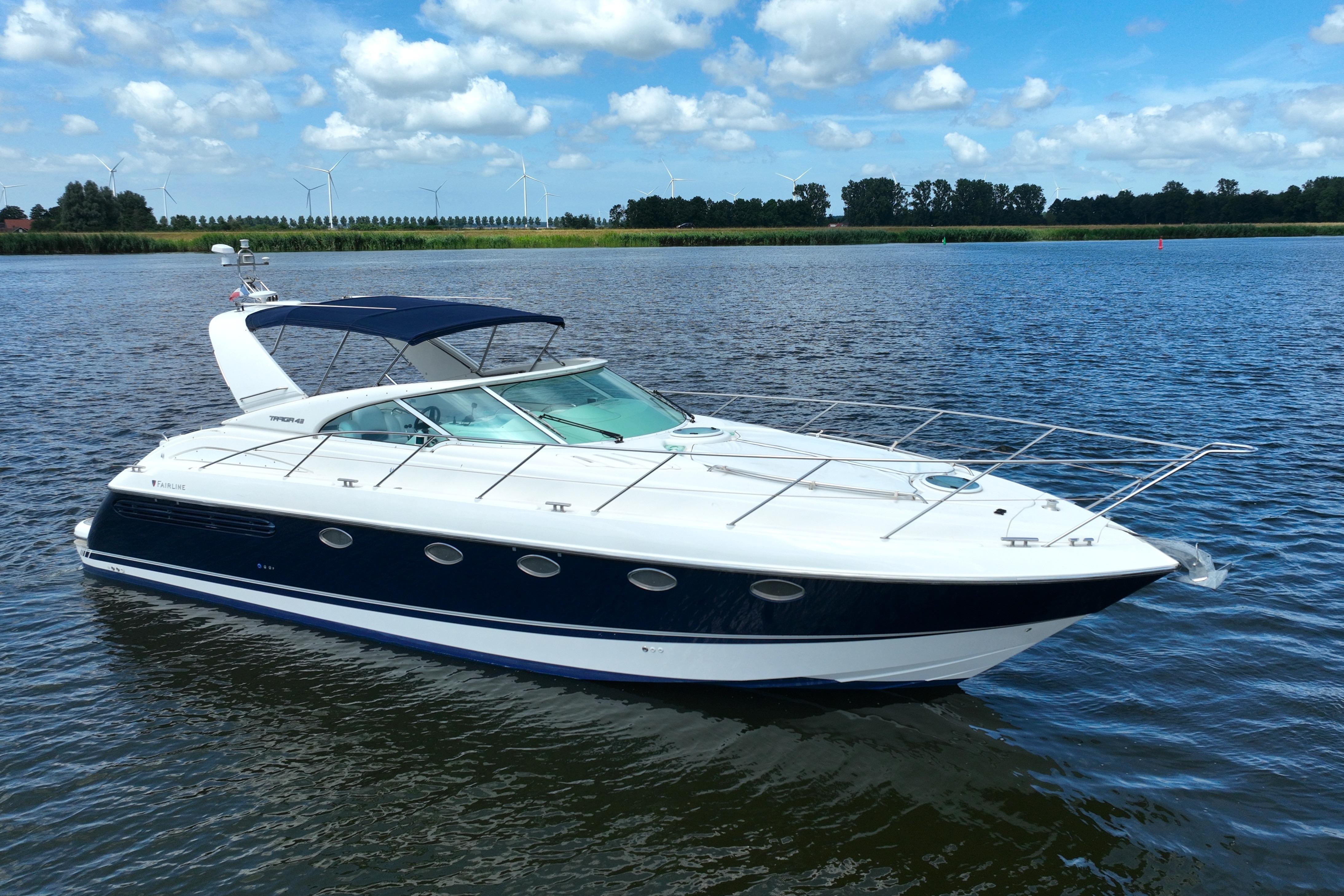 2002 Fairline Targa 43 yacht on a serene lake under a blue sky.
