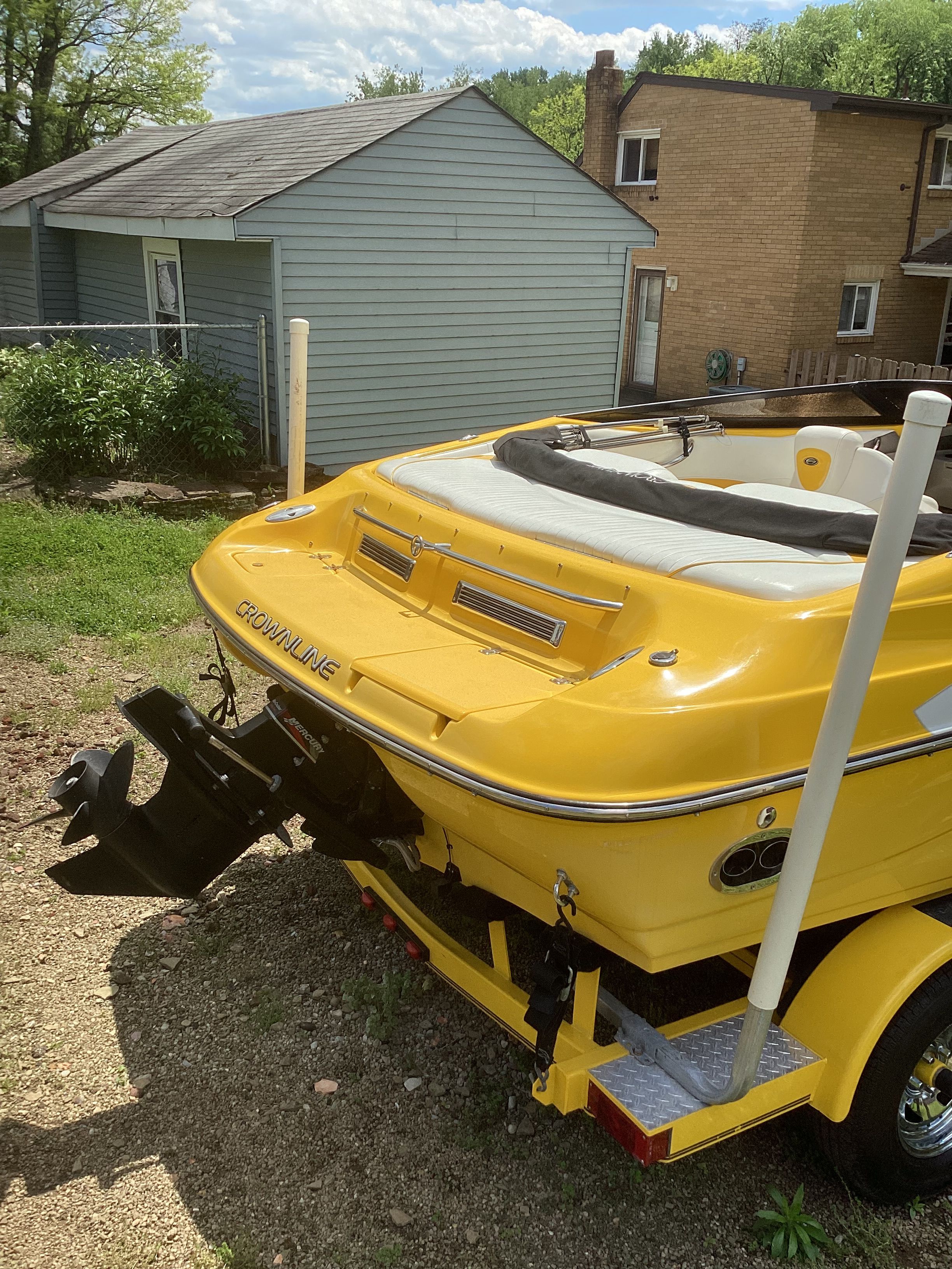 Yellow 2005 Crownline 202 BR LPX boat on trailer in yard.
