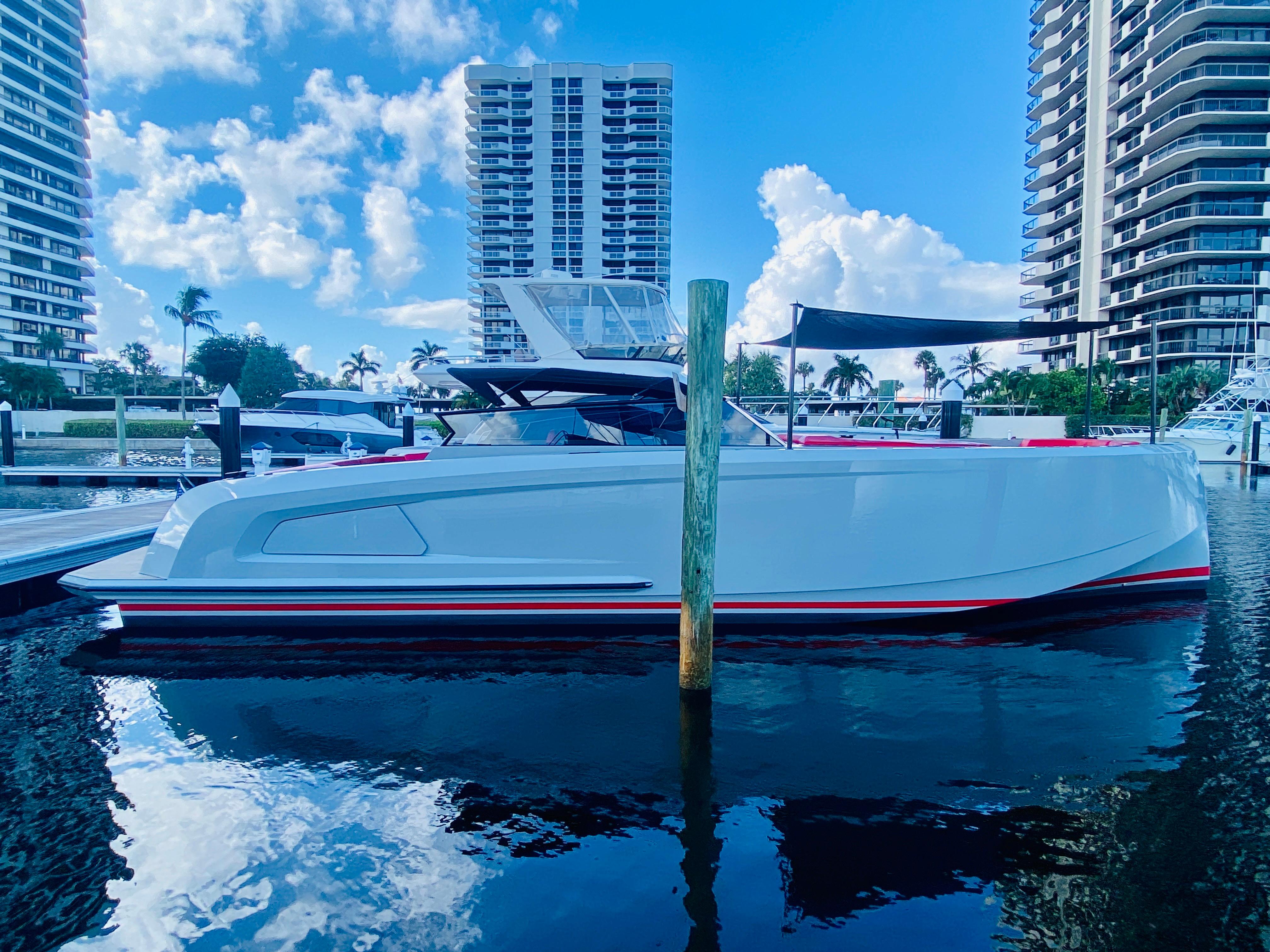 2020 Vanquish VQ45 yacht docked in marina, surrounded by tall buildings and blue sky.