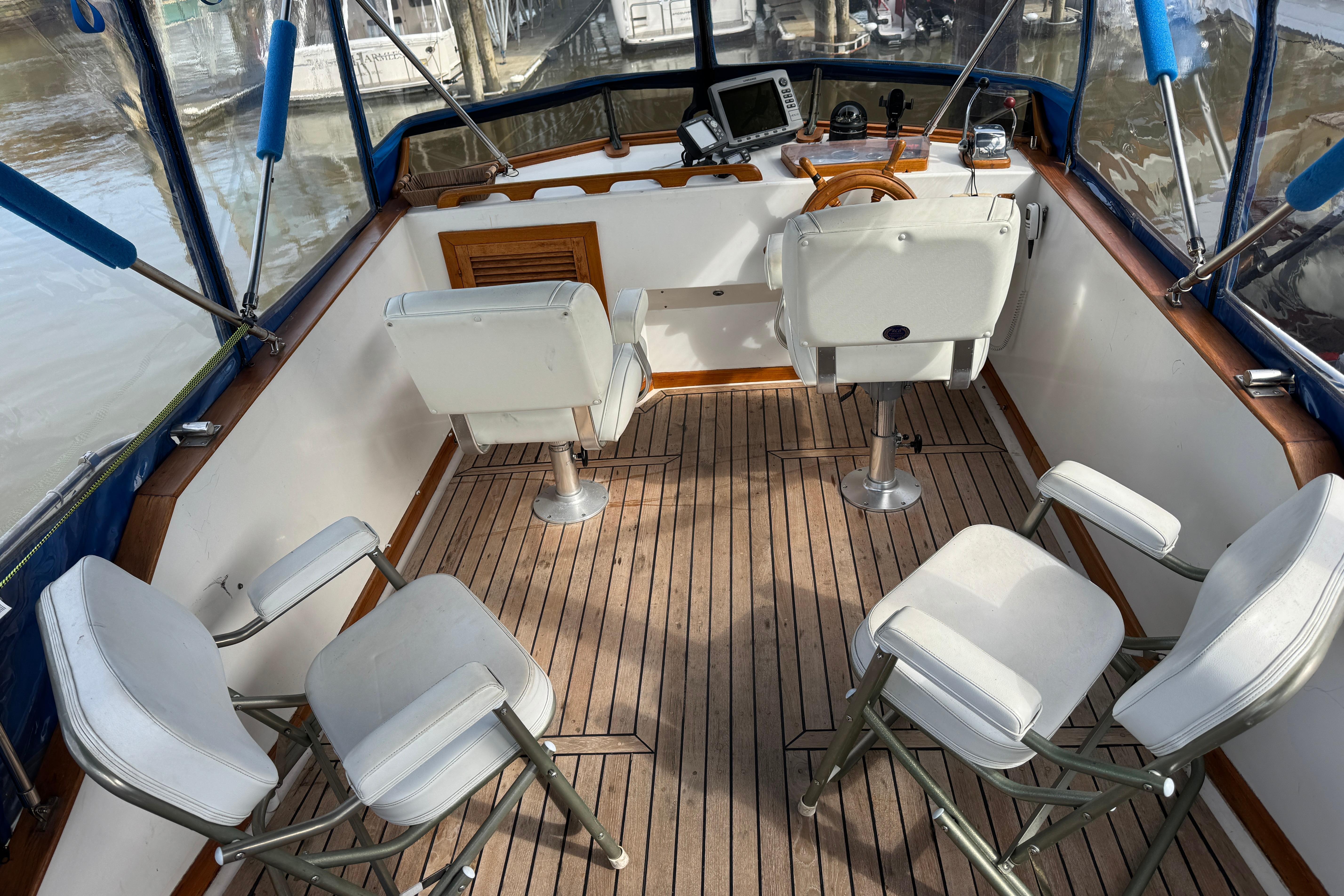 1980 CHB 35 boat cockpit with white seating, wooden flooring, and navigation equipment.