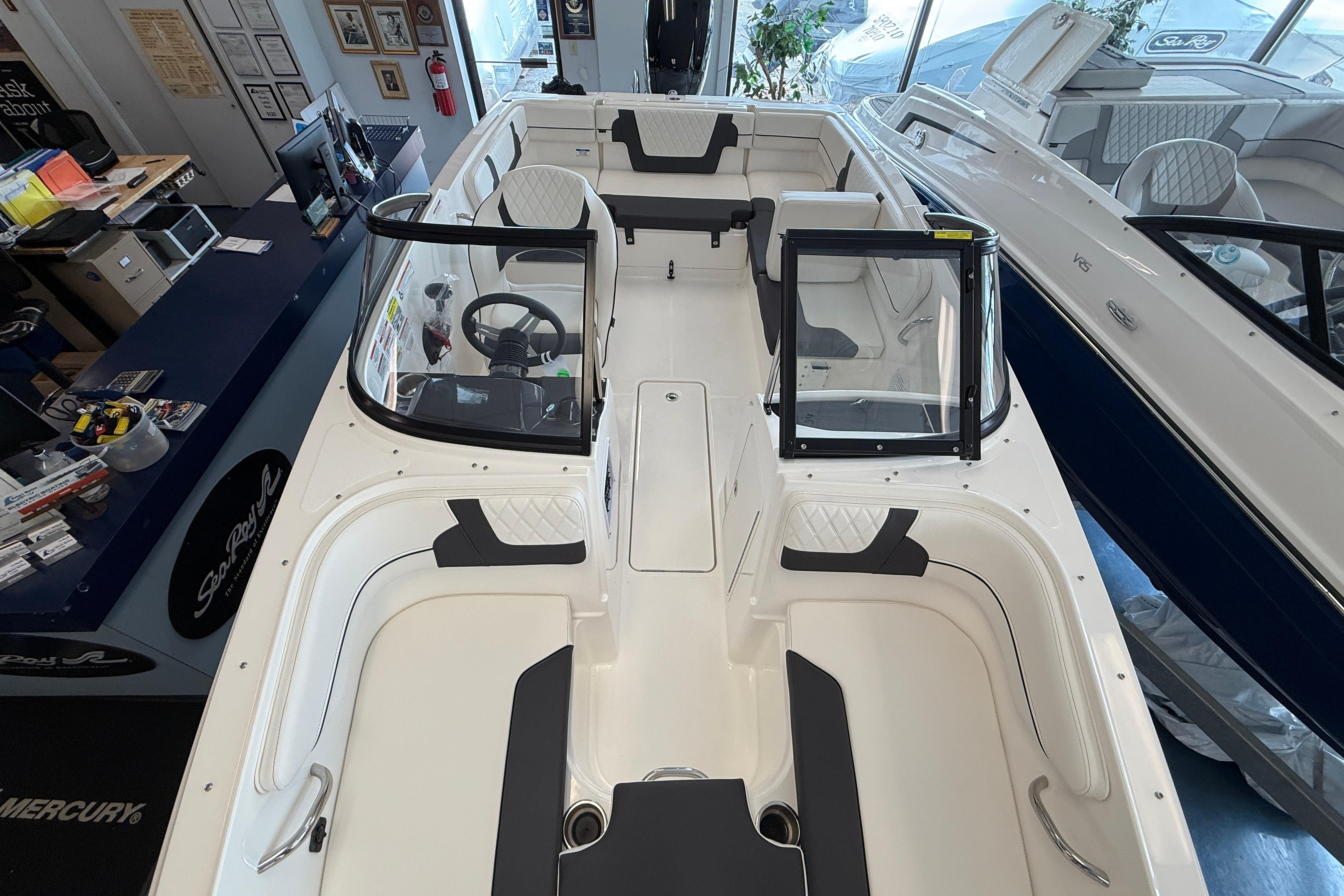 2025 Bayliner VR4 Bowrider OB interior view, showcasing seating and steering area in showroom.
