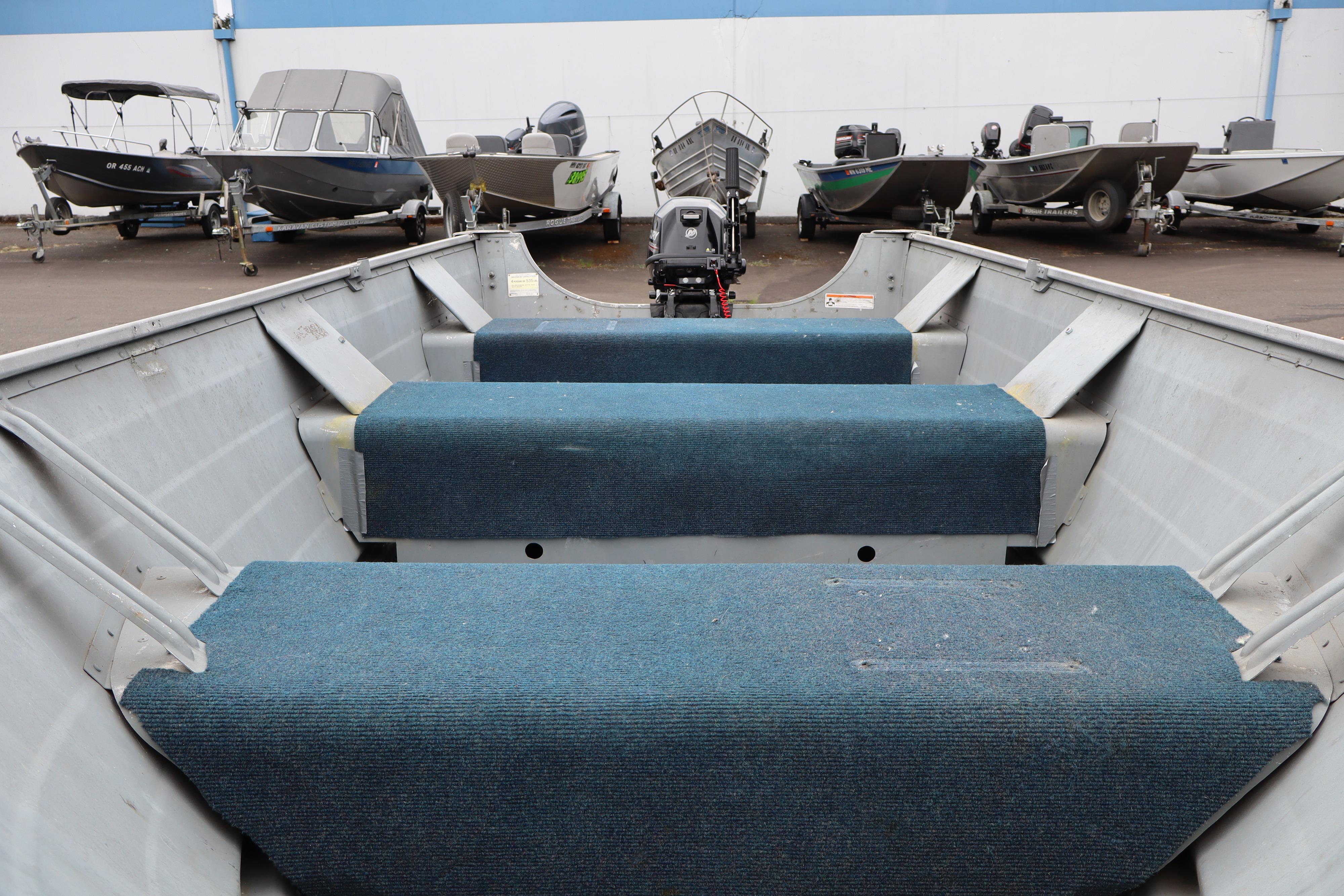 2003 Smoker Craft Alaskan 13 boat interior with blue carpeted seating, parked among other boats.