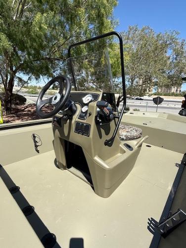 2025 Tracker Grizzly 1860 CC boat console with steering wheel, outdoors under clear sky.