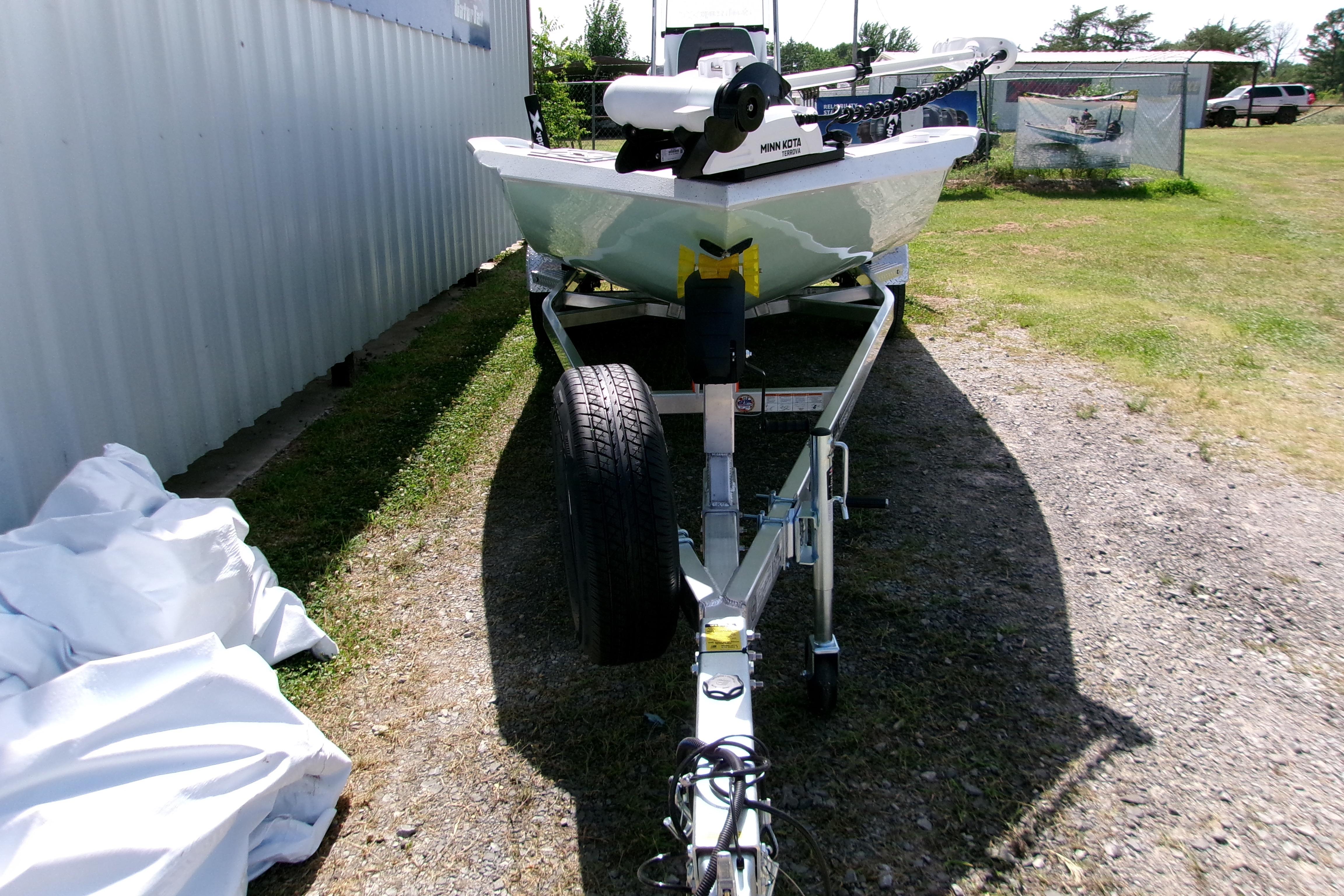 2027 Xpress H22B Bay boat on trailer, parked outdoors near a metal building.
