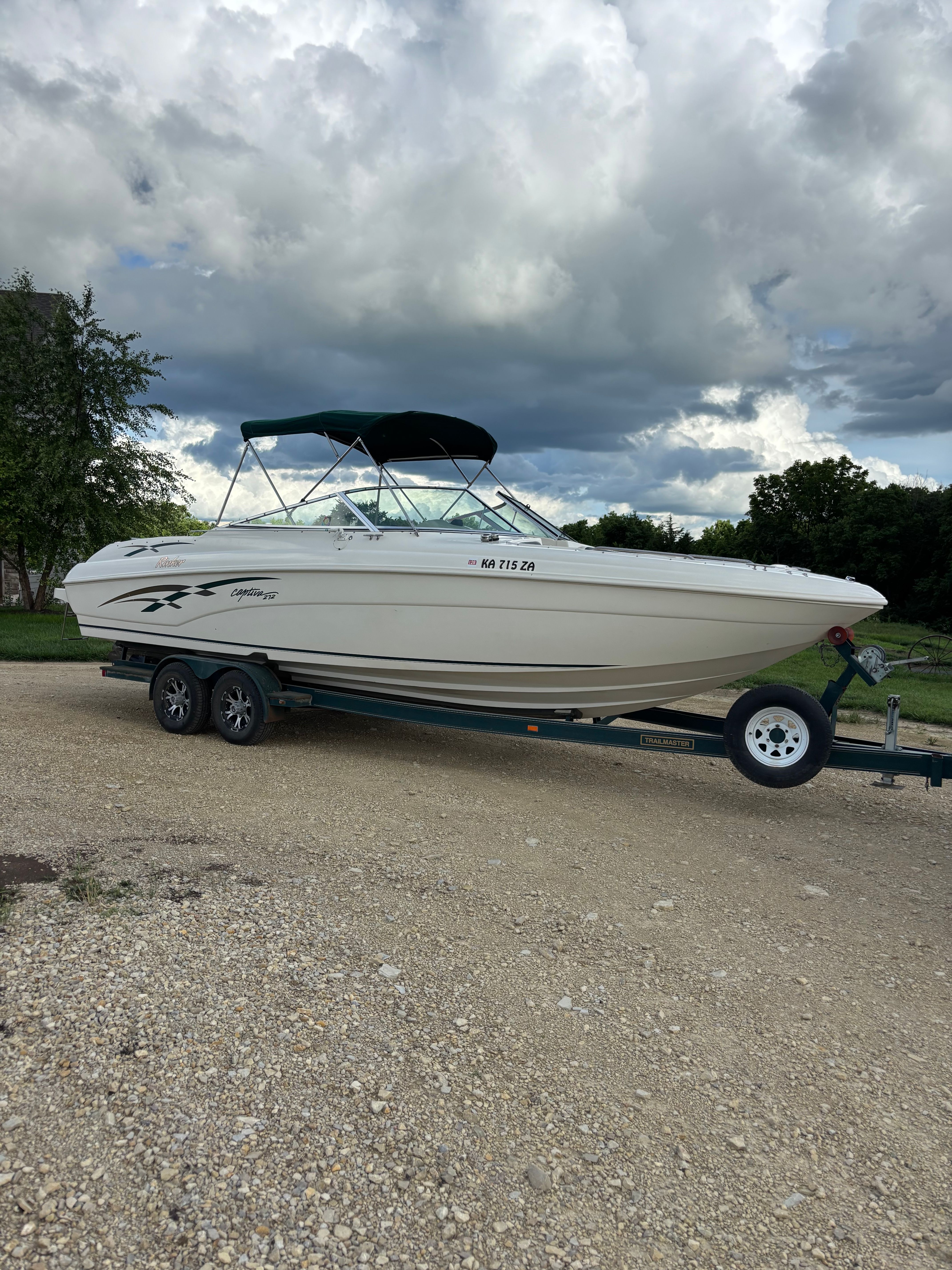 1999 Rinker Captiva 272 boat on trailer under cloudy sky.