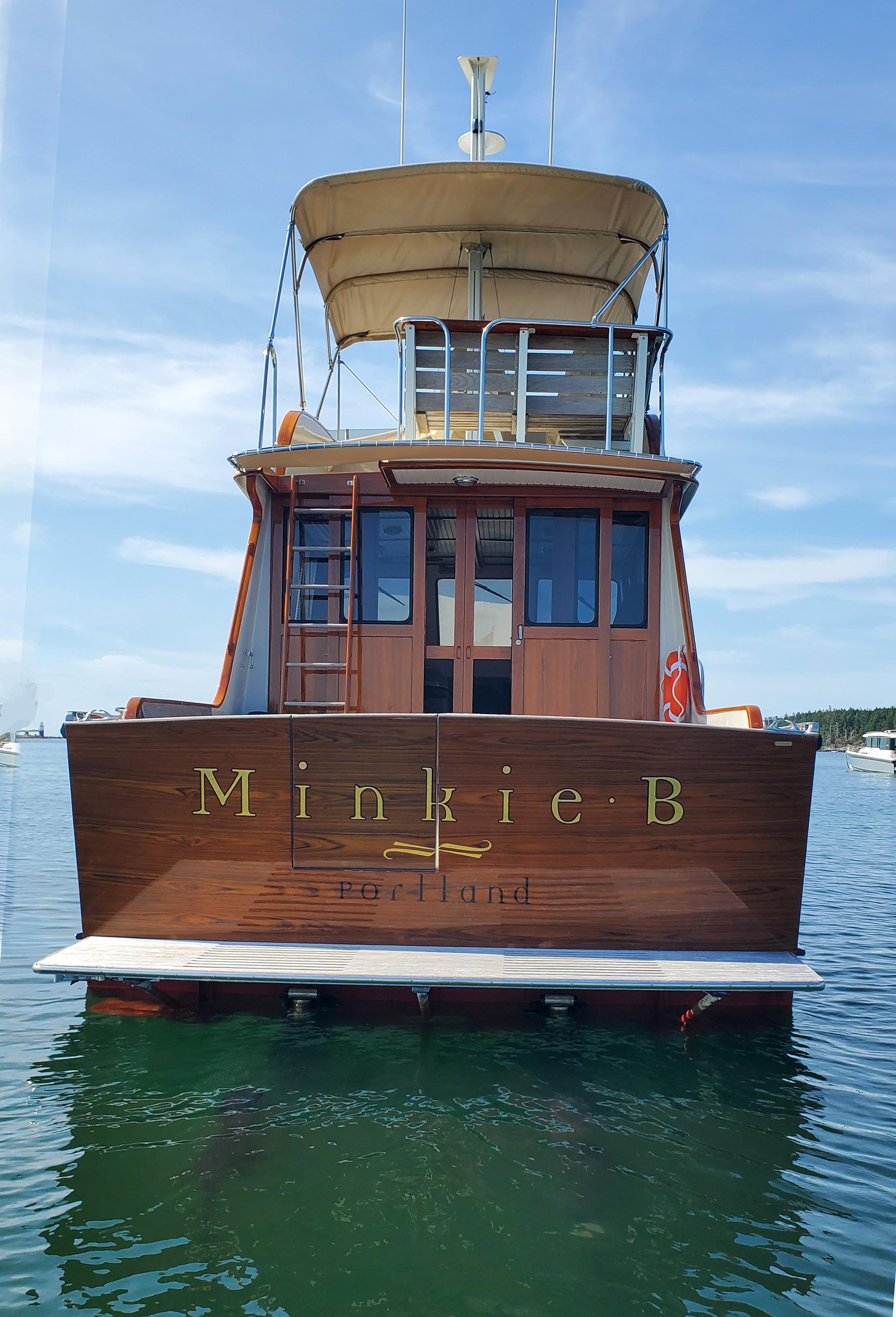 1997 Lyman-Morse Custom Flybridge yacht on water, rear view, clear sky.