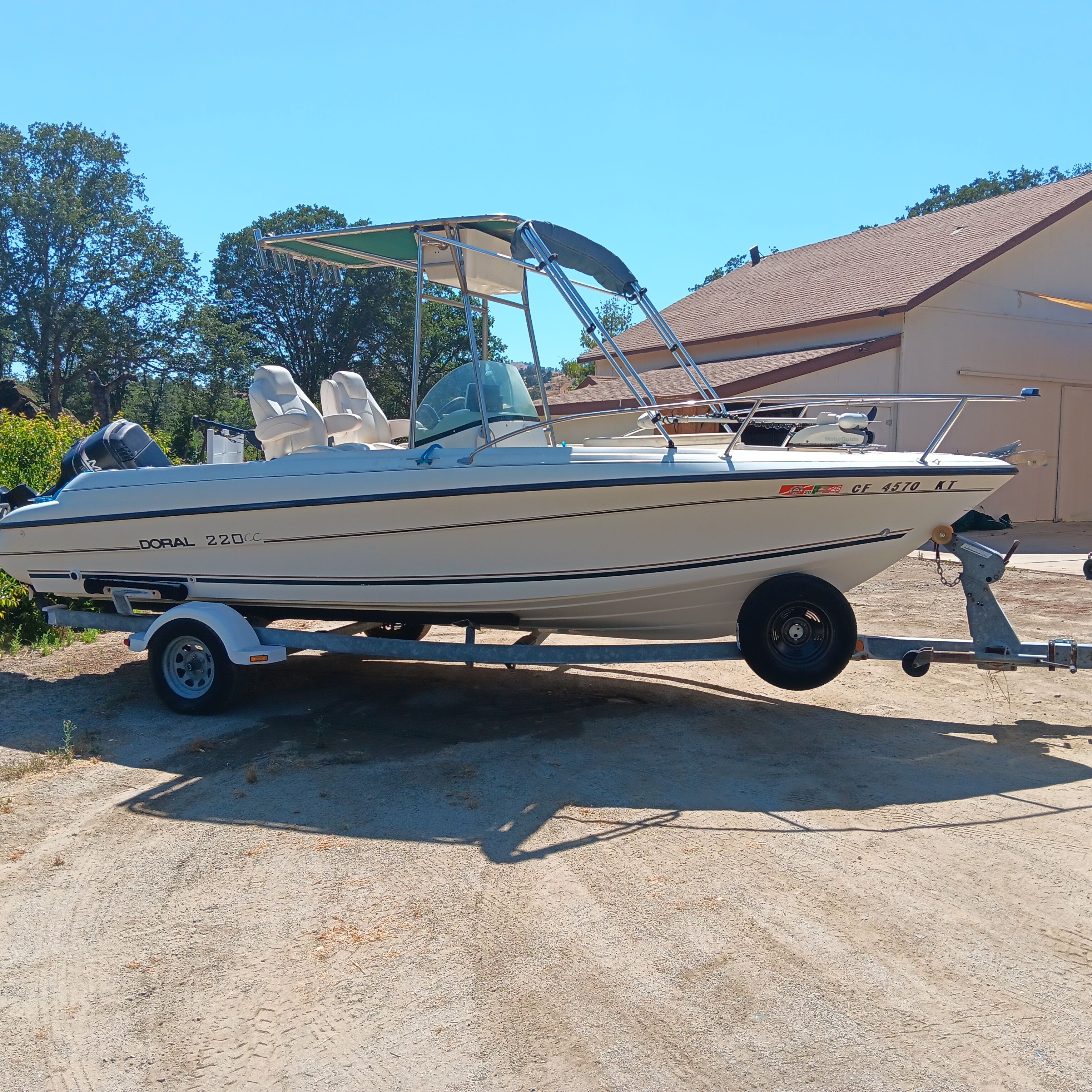 A 1998 Doral Ibiza 22 CC boat on a trailer in a sunny yard.