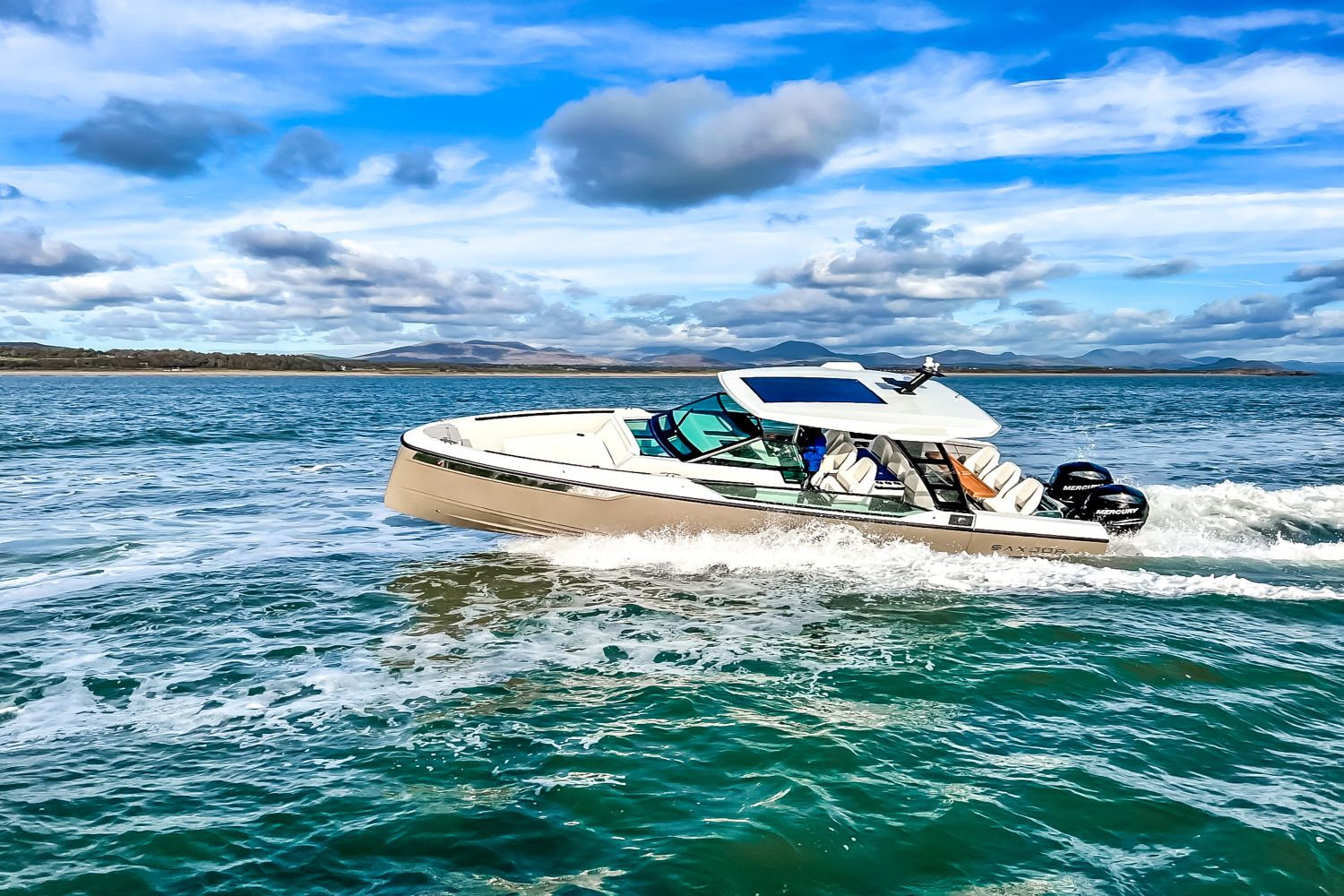 A 2027 Saxdor SX320 GTO cruising on the water with a blue sky and clouds in the background.