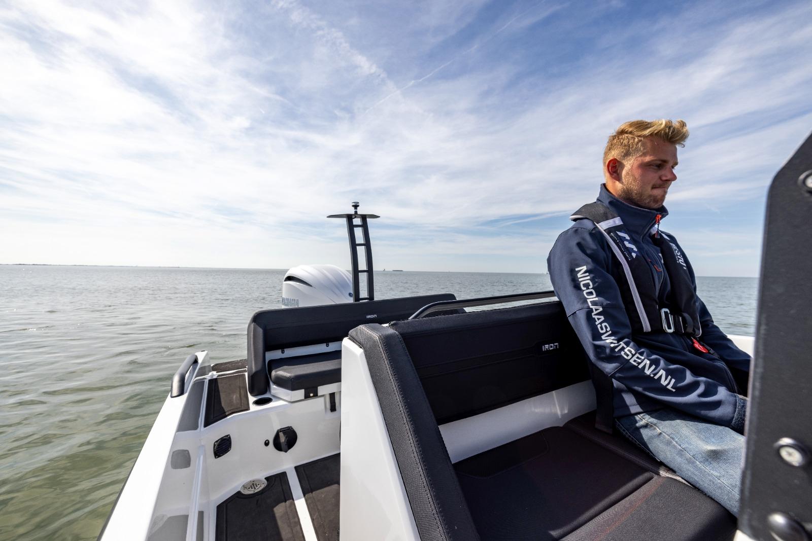 Man sitting on Iron 707 boat, 2022 model, enjoying a calm sea view.