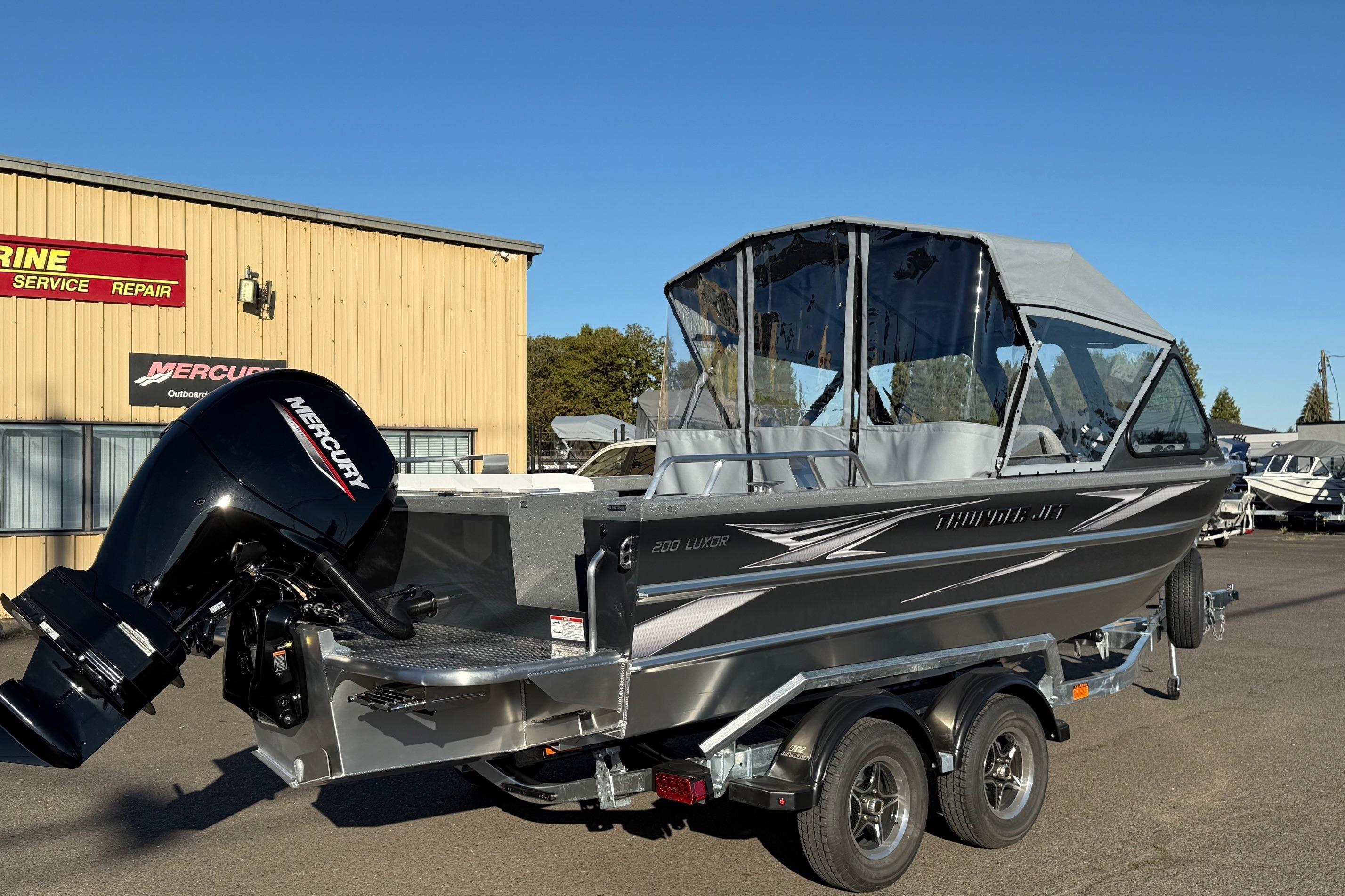 2026 Thunder Jet 200 Luxor boat with Mercury outboard motor, parked outside a marine service shop.