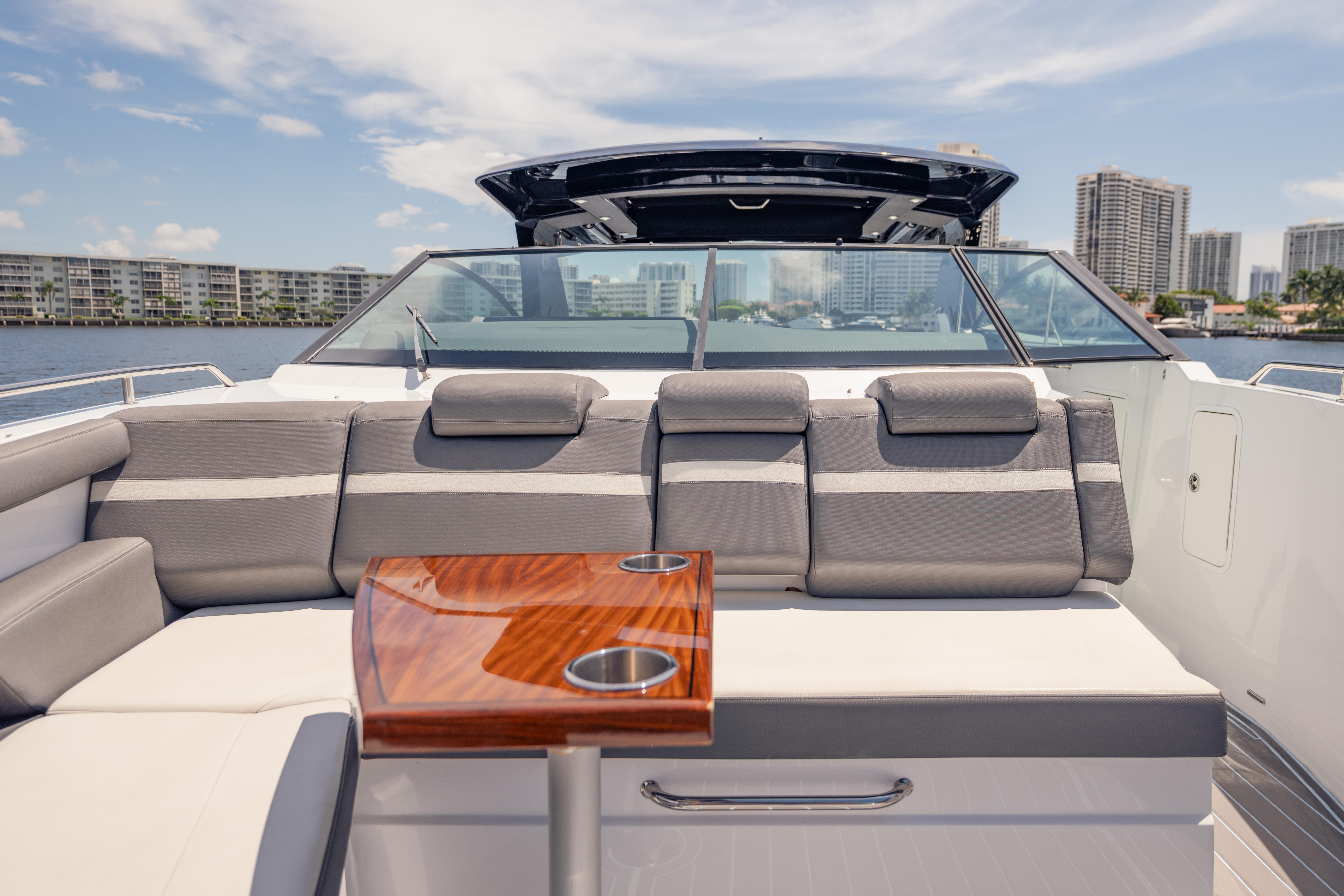 2021 Cruisers Yachts 38 GLS luxury boat interior with seating and table, cityscape in background.