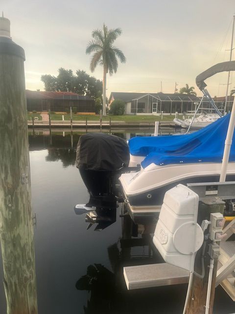 A white boat with a blue cover is docked in calm waters.
