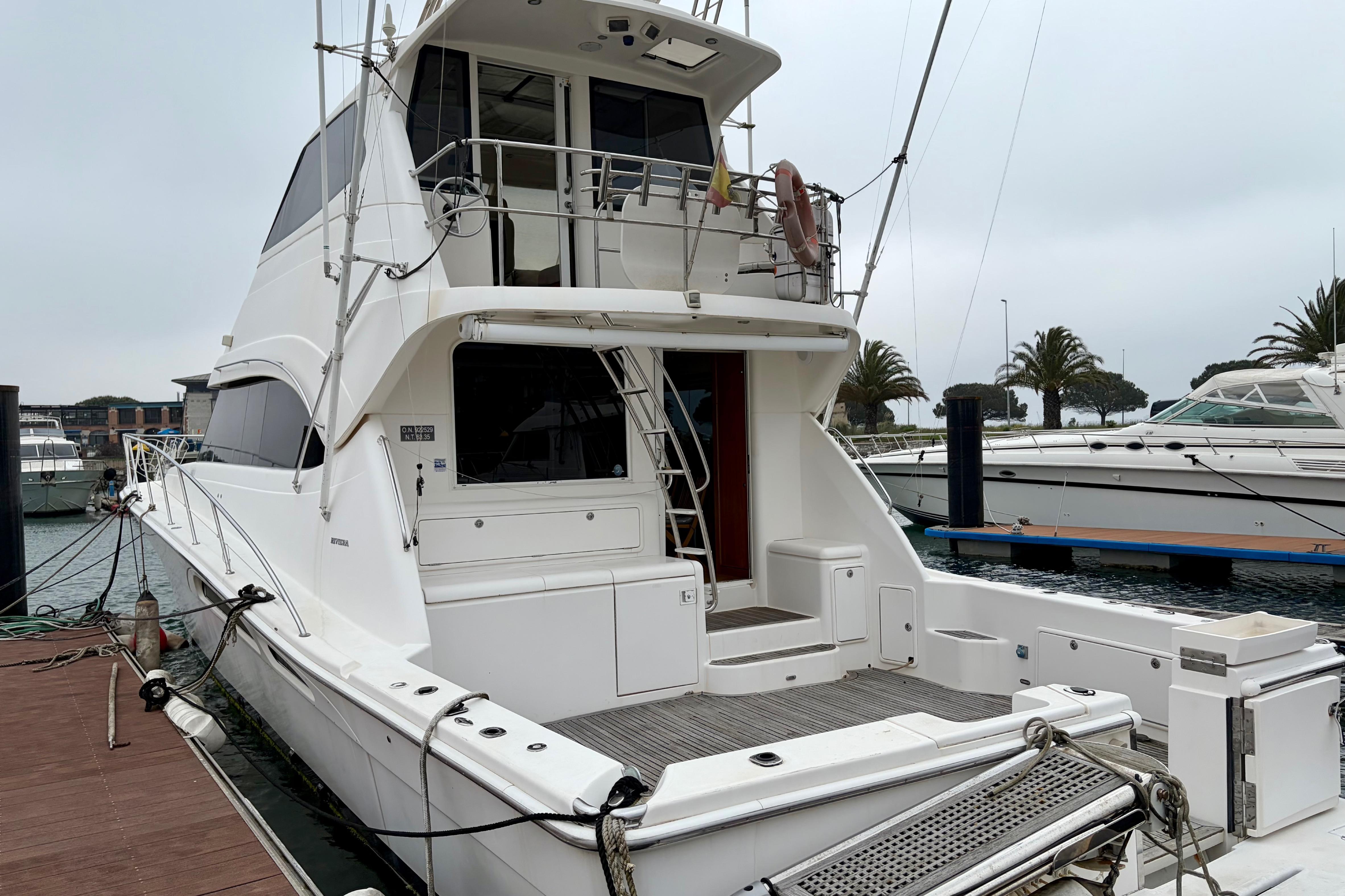 2003 Riviera 60 Flybridge yacht docked at marina, showcasing spacious deck and sleek design.