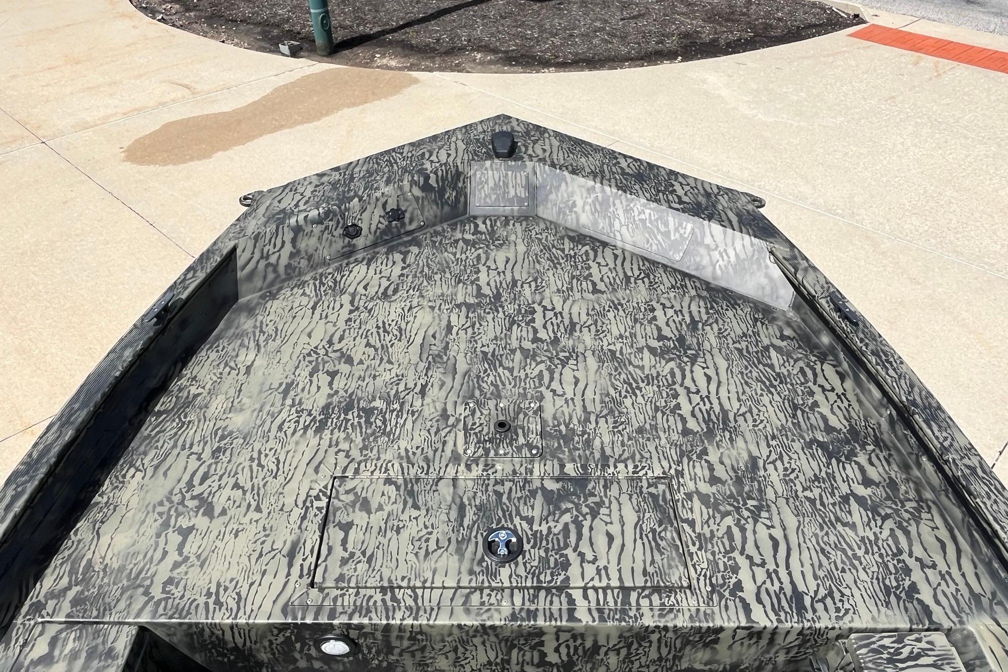 2026 Tracker Grizzly 1654 T Sportsman boat with camouflage pattern on a concrete surface.