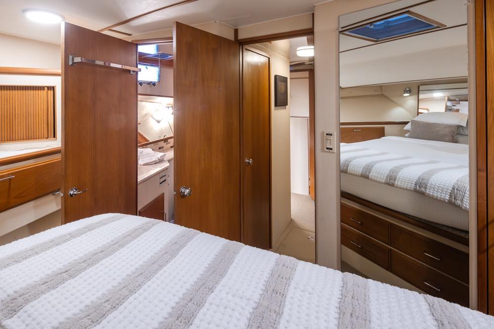 Luxurious bedroom interior of 1991 Tollycraft 57 Pilothouse Motor Yacht with wood accents.