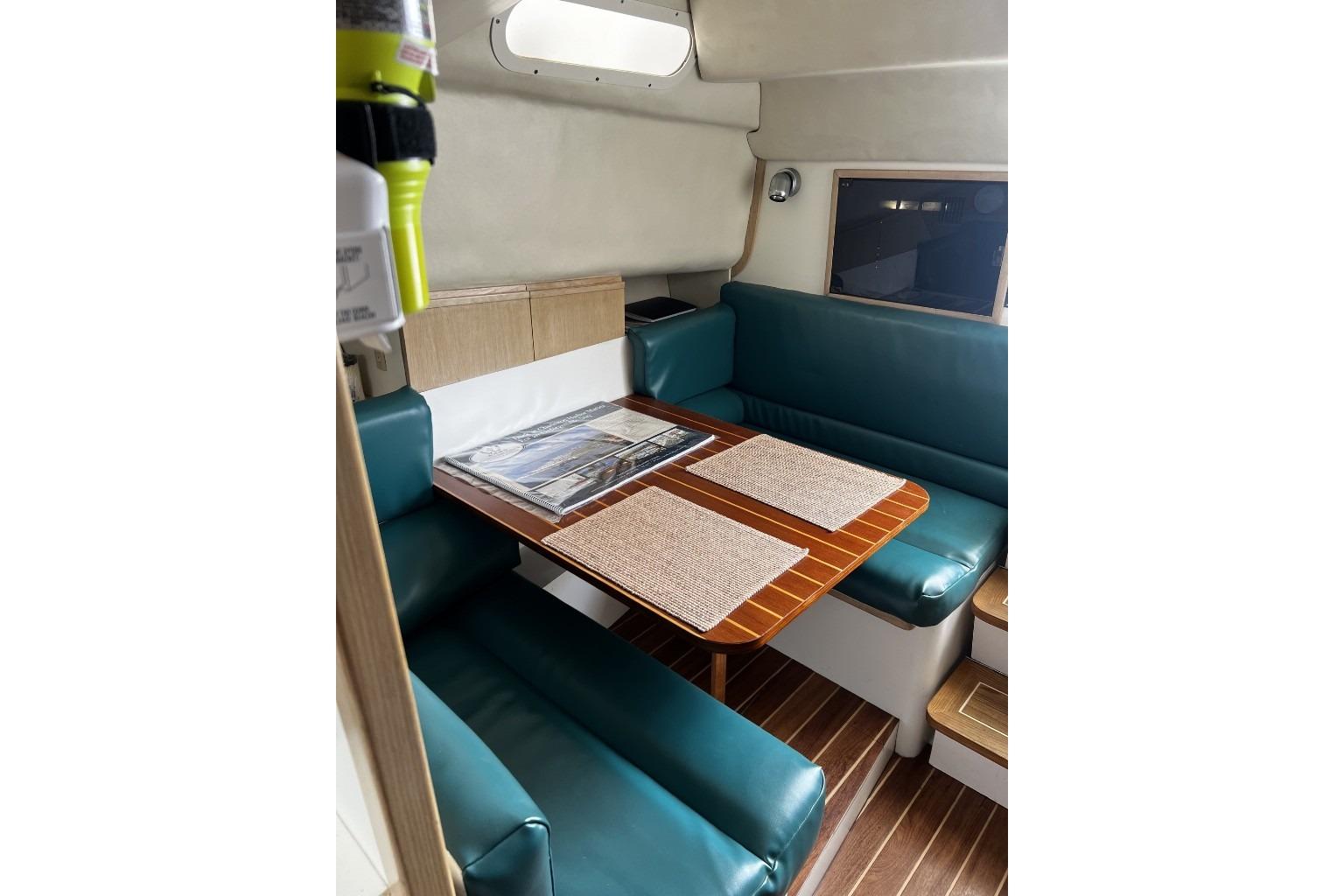 Interior of 1993 Blackfin 31 Combi boat with teal seating and wooden table.