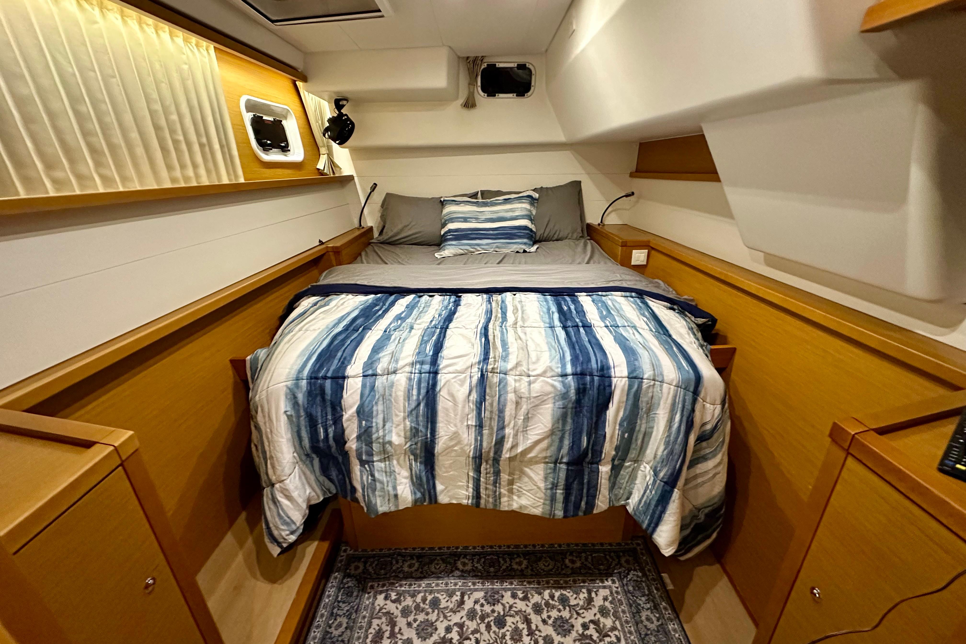 Cozy cabin interior of 2016 Lagoon 450 S yacht with striped bedding.