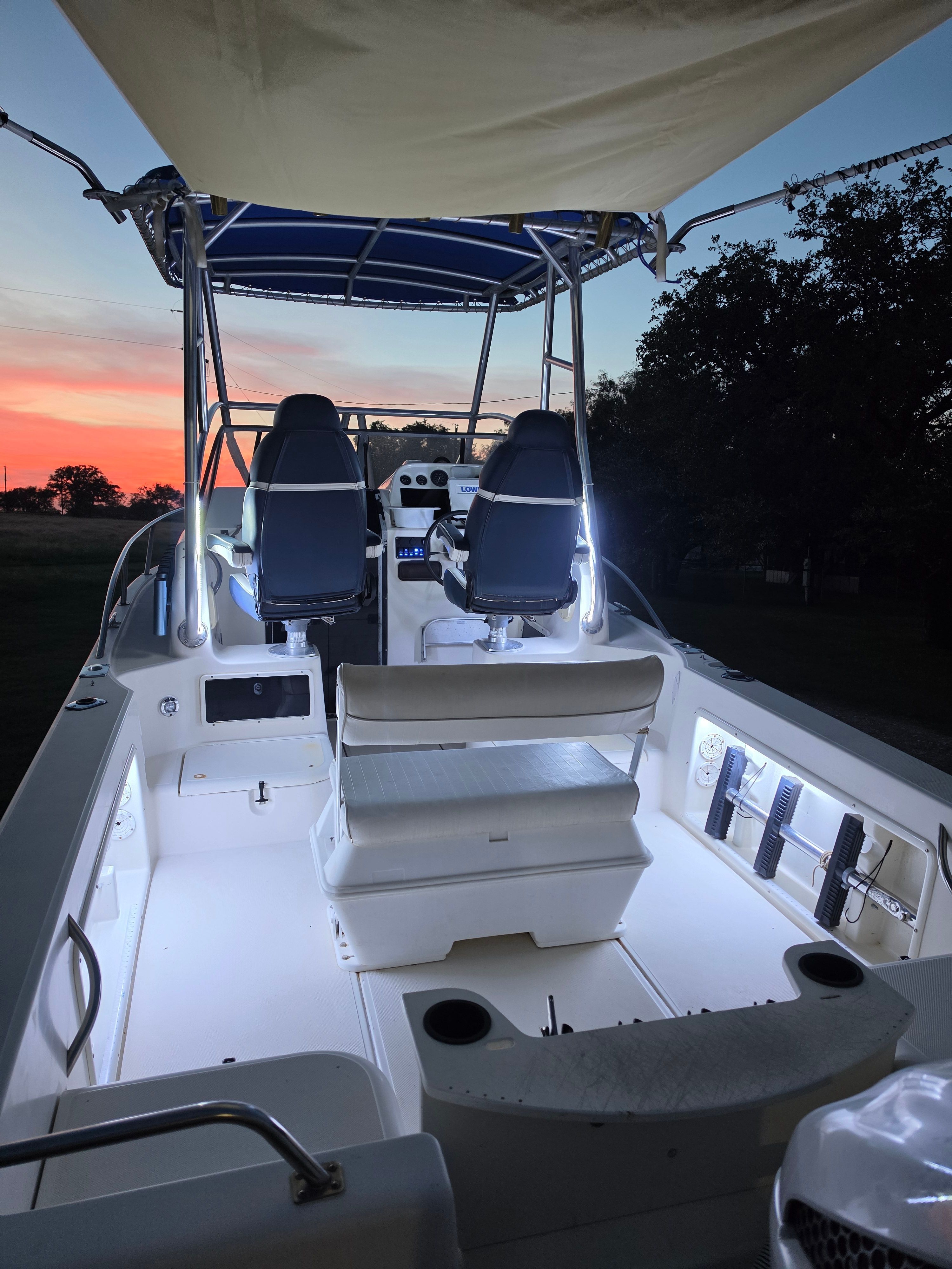The image shows the cockpit of a Hydra-Sports 2450 boat at sunset. It features two seats and a lit dashboard.