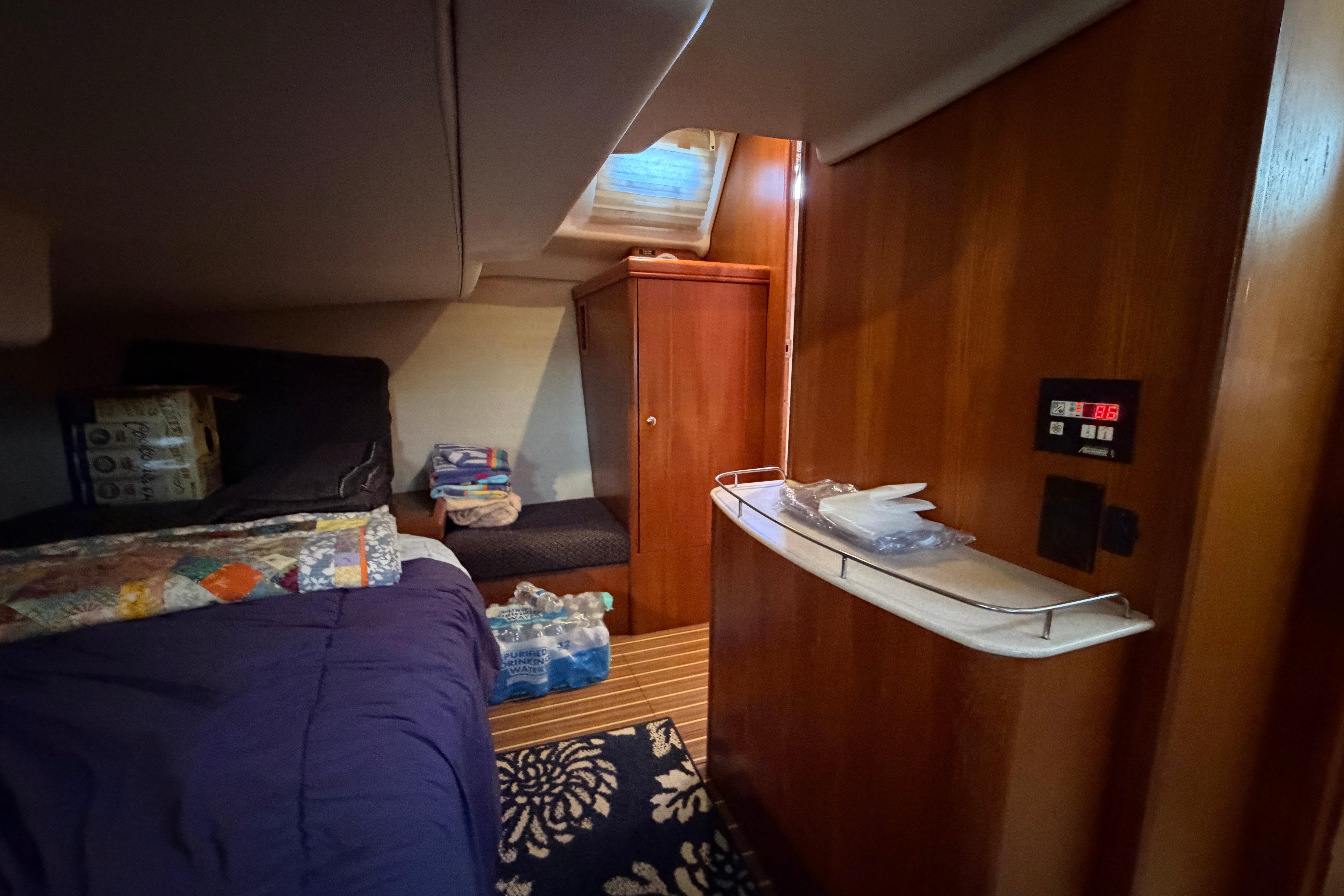 Cozy cabin interior of 2005 Hunter 38 sailboat with wood paneling and bedding.