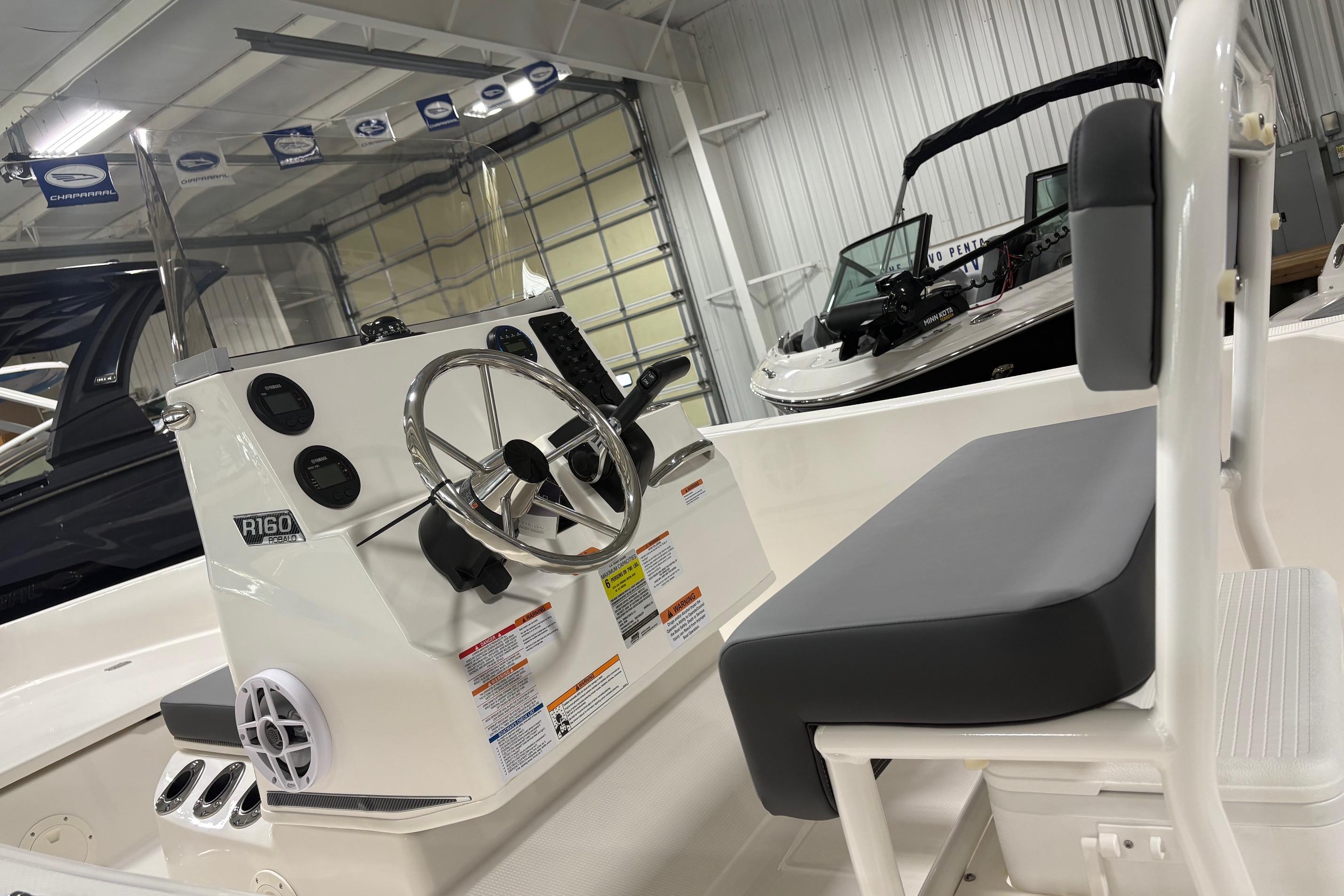 2026 Robalo R160 Center Console boat interior with steering wheel and seating in showroom.