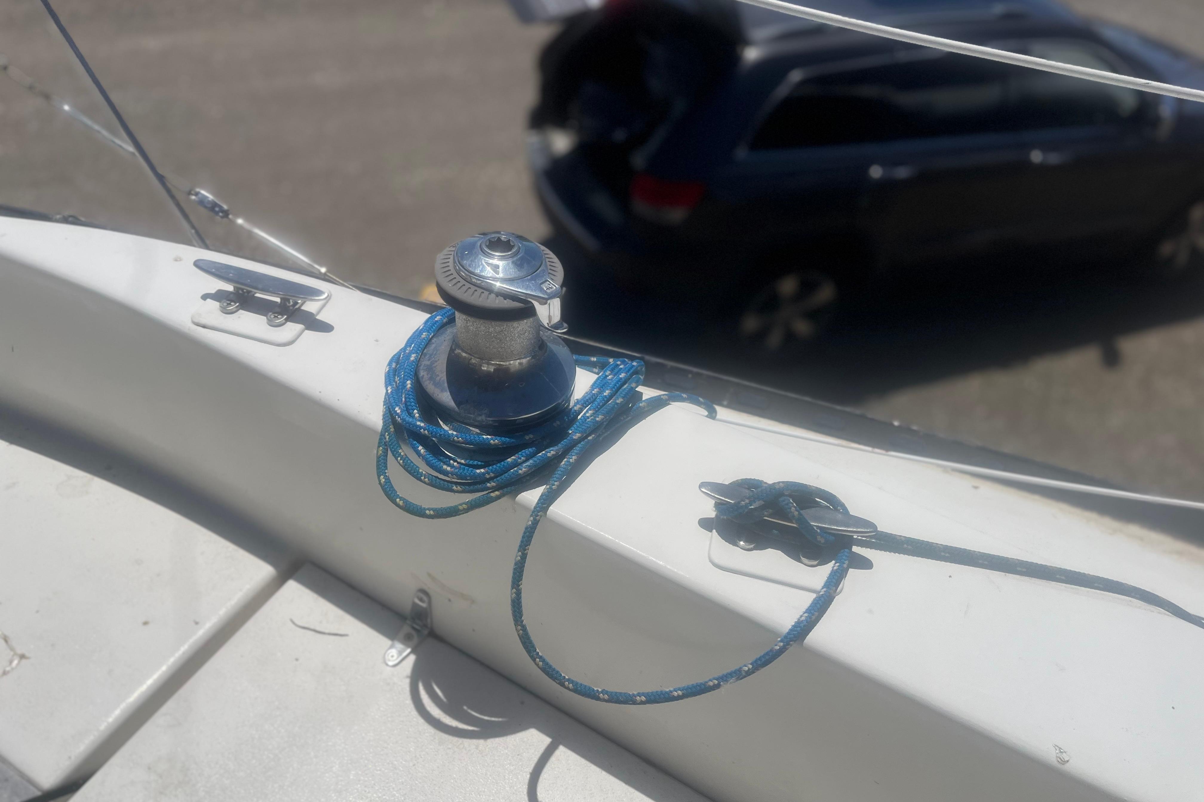 Winch and rope on a 1972 C&C 30 sailboat deck, with a car in the background.