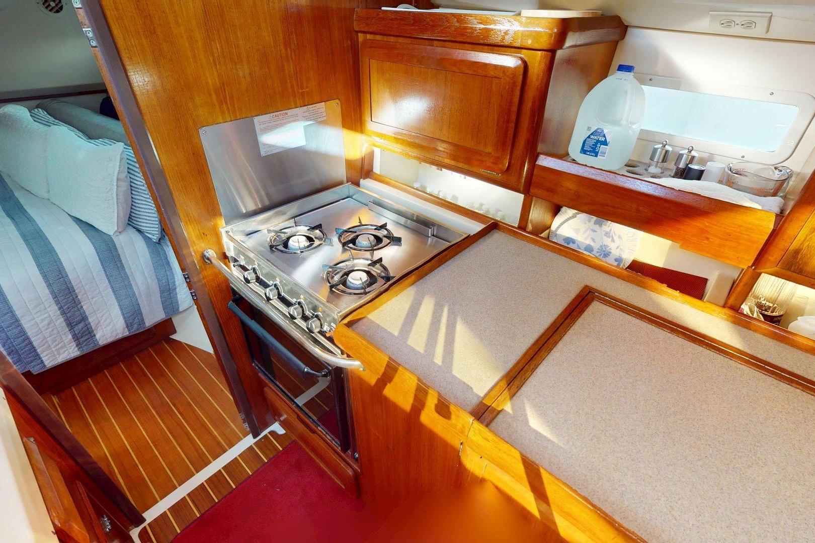 Cozy kitchen area in a 1997 Hunter Legend 40.5 yacht, featuring a stove and wooden cabinetry.