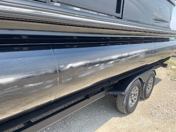 2023 Regency 250 LE3 pontoon boat on trailer, side view, shiny black exterior.