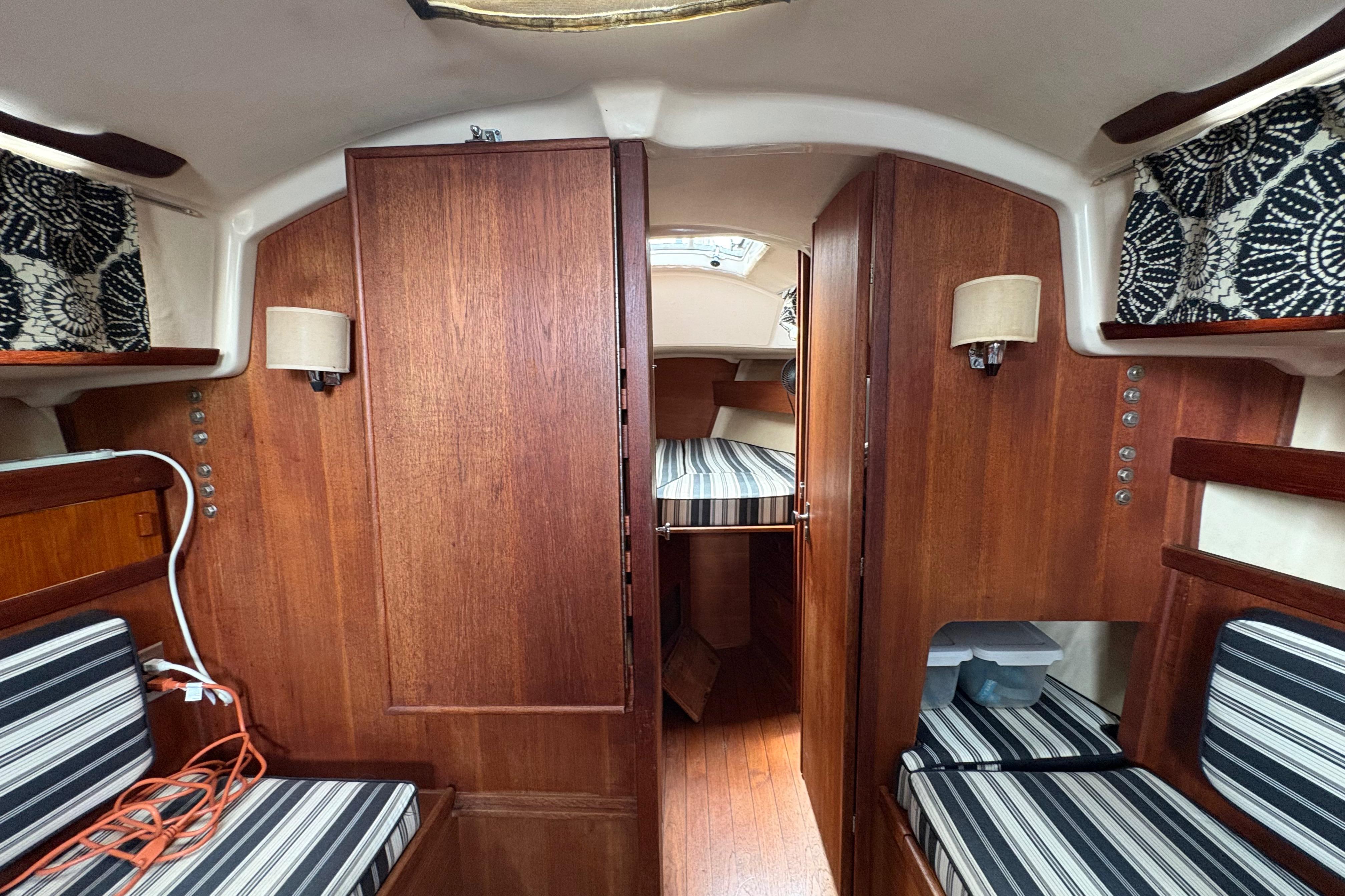 Interior of a 1981 Sabre 31 sailboat with wood paneling and striped cushions.