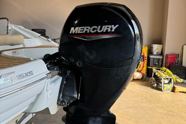 2023 Crownline 215 XS boat with Mercury outboard motor in garage.
