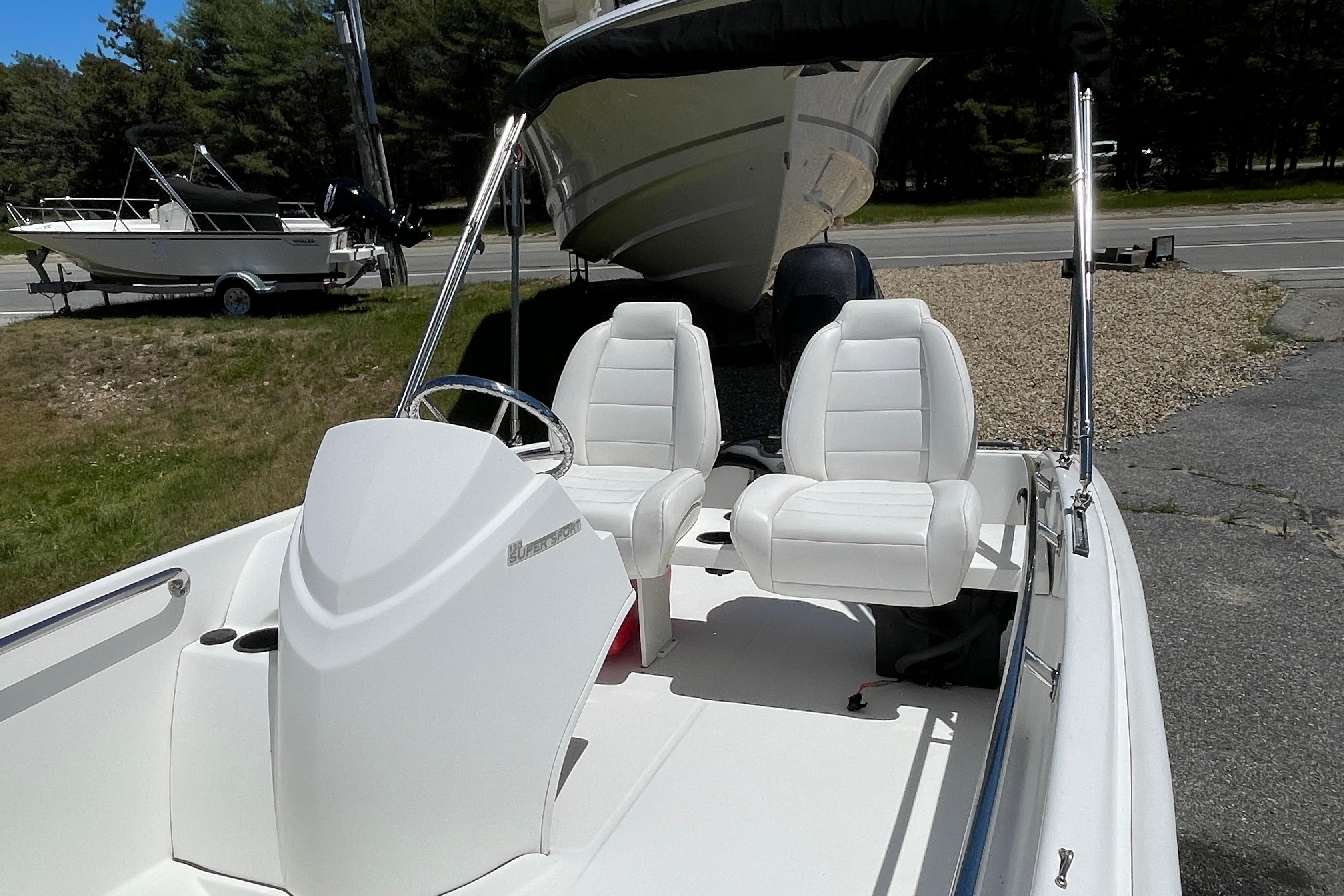 2017 Boston Whaler 130 Super Sport boat with white seating and steering wheel, parked outdoors.