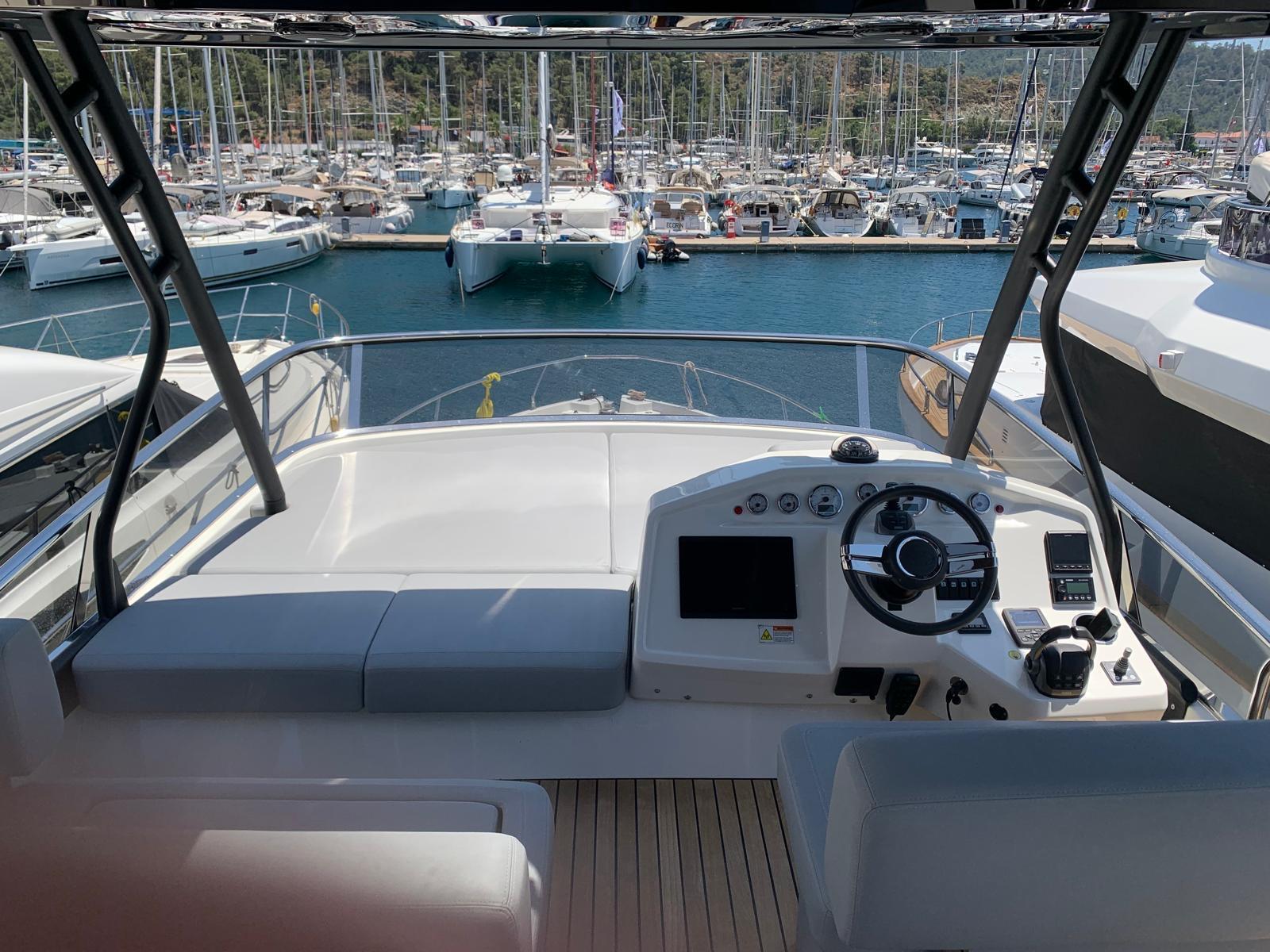 2023 Cranchi F 52 yacht helm with marina view, featuring modern controls and seating.