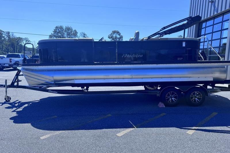 2027 Manitou Aurora 23 RF SHP pontoon boat on trailer in parking lot.