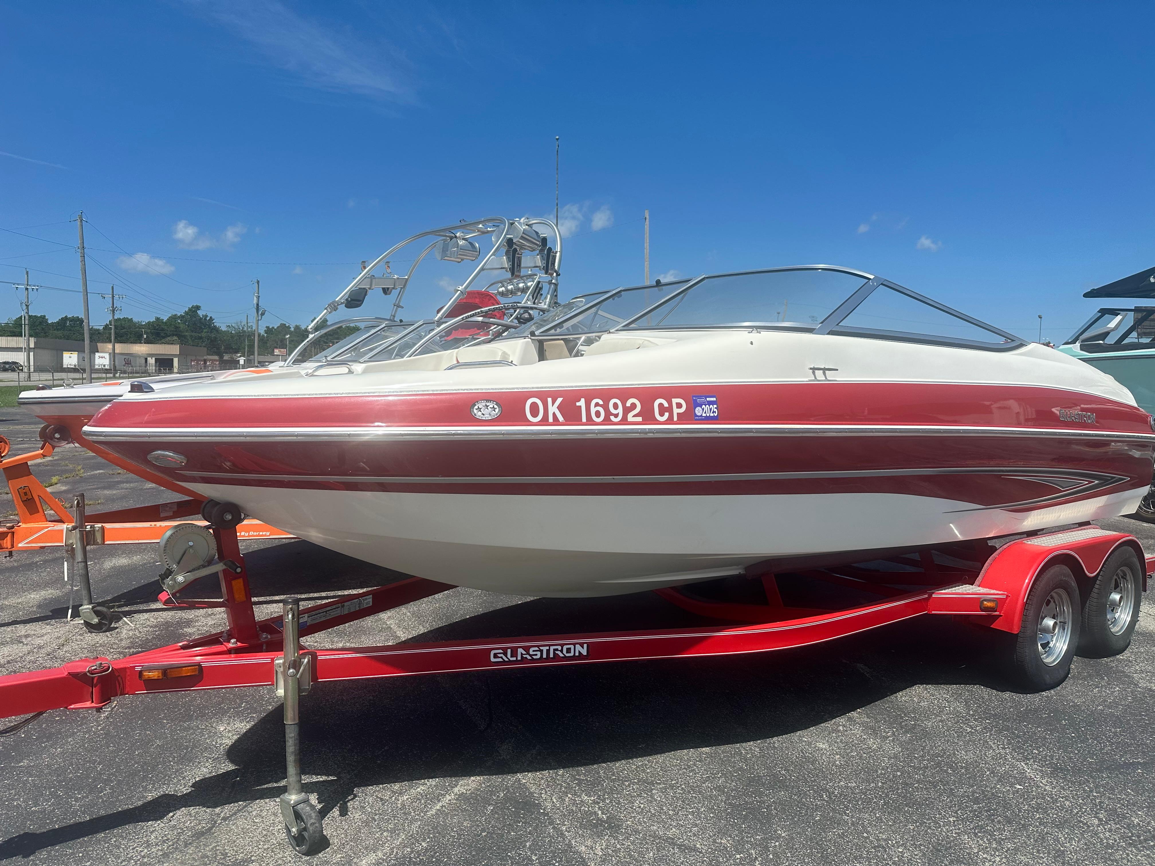 2008 Glastron 205 GX boat on red trailer under clear blue sky.