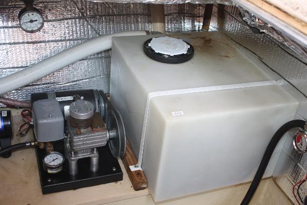 A water tank and pump in a boat's engine compartment.