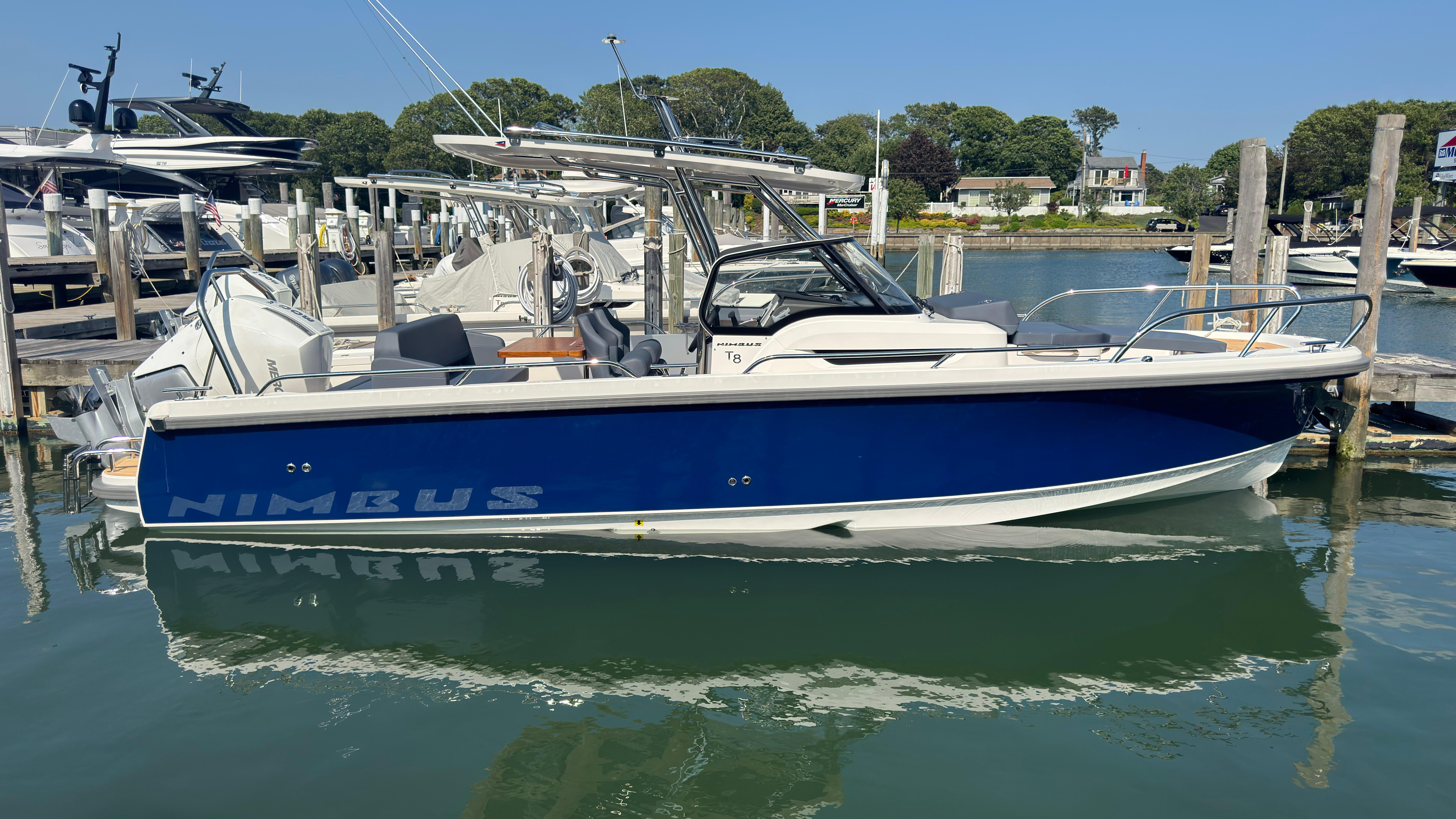 2024 Nimbus T8 boat docked in a marina, featuring a sleek blue and white design.