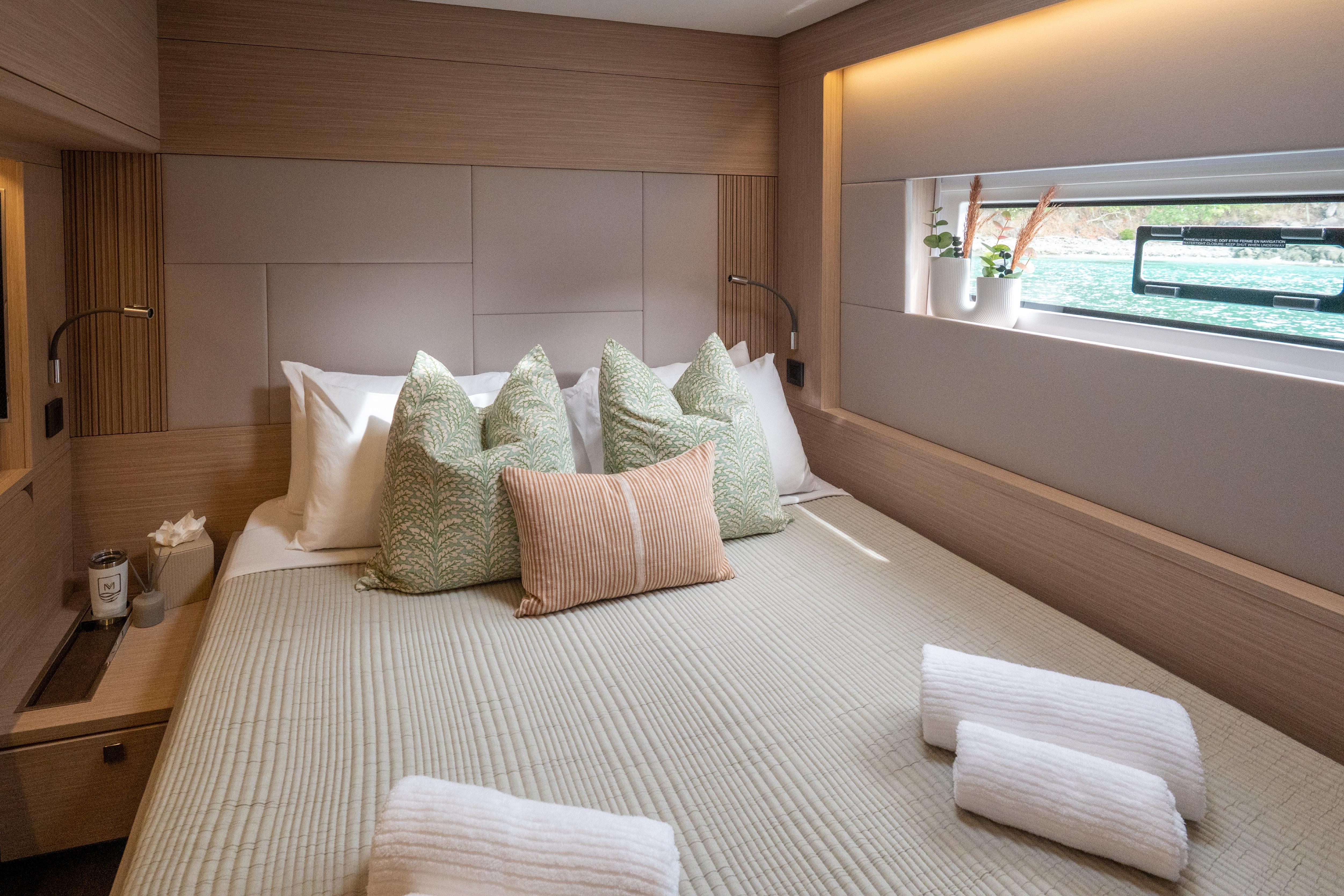 Luxurious bedroom interior of 2026 Lagoon 60 yacht with elegant decor and window view.
