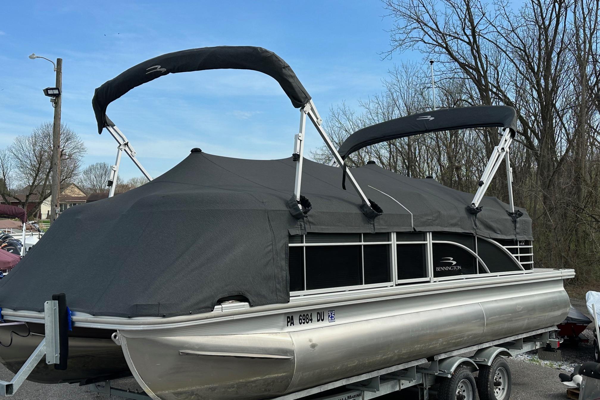 2017 Bennington 22 GPD pontoon boat with cover on trailer, parked outdoors.