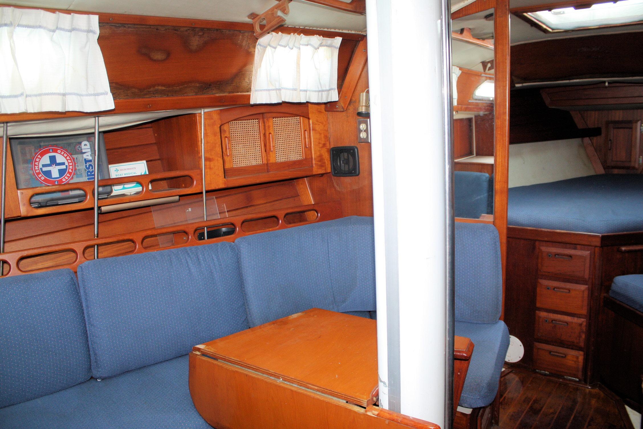 Interior of 1987 Ericson 38-200 sailboat with blue seating and wooden cabinetry.