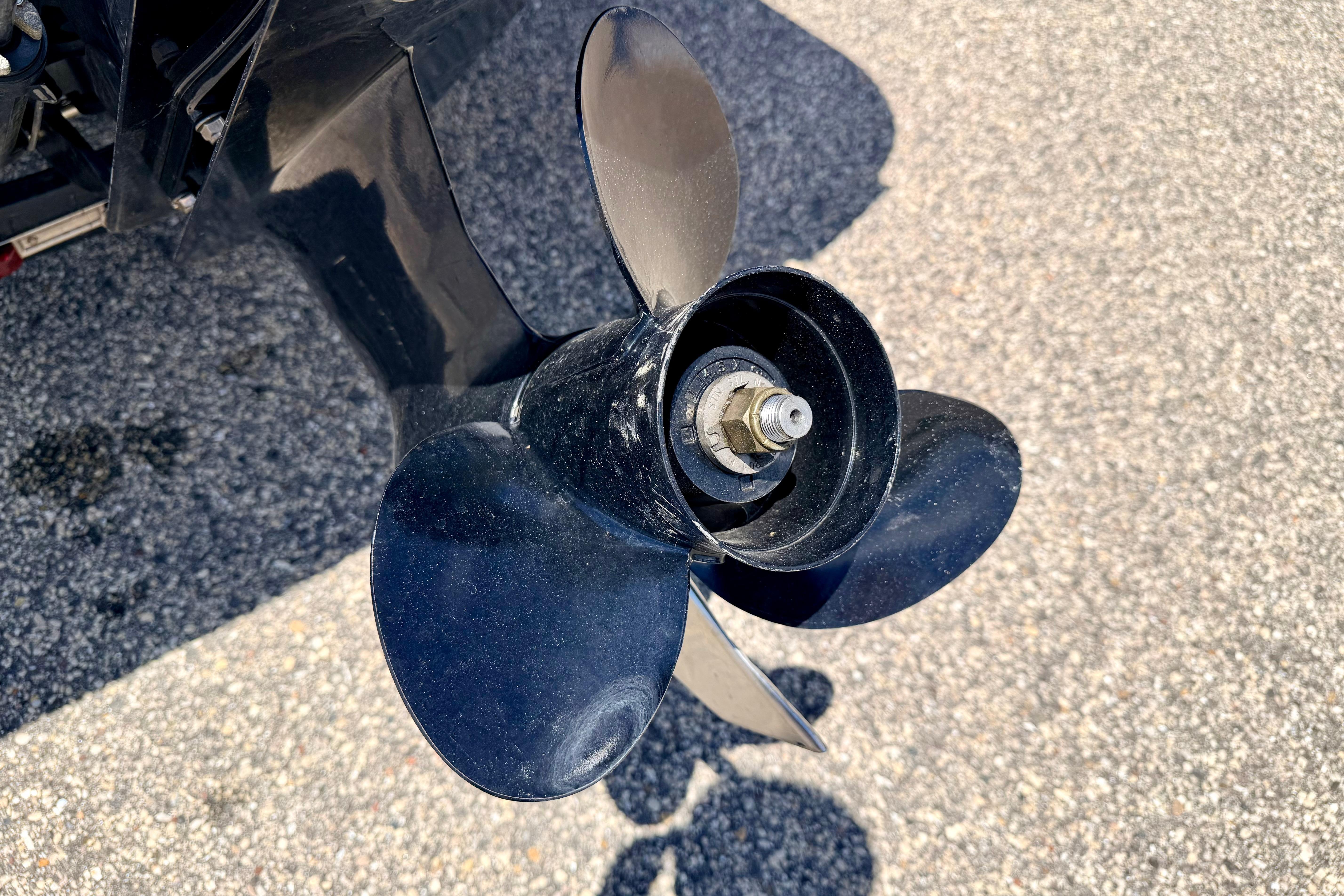 Close-up of a 2018 Glastron GT 185 boat propeller on asphalt surface.