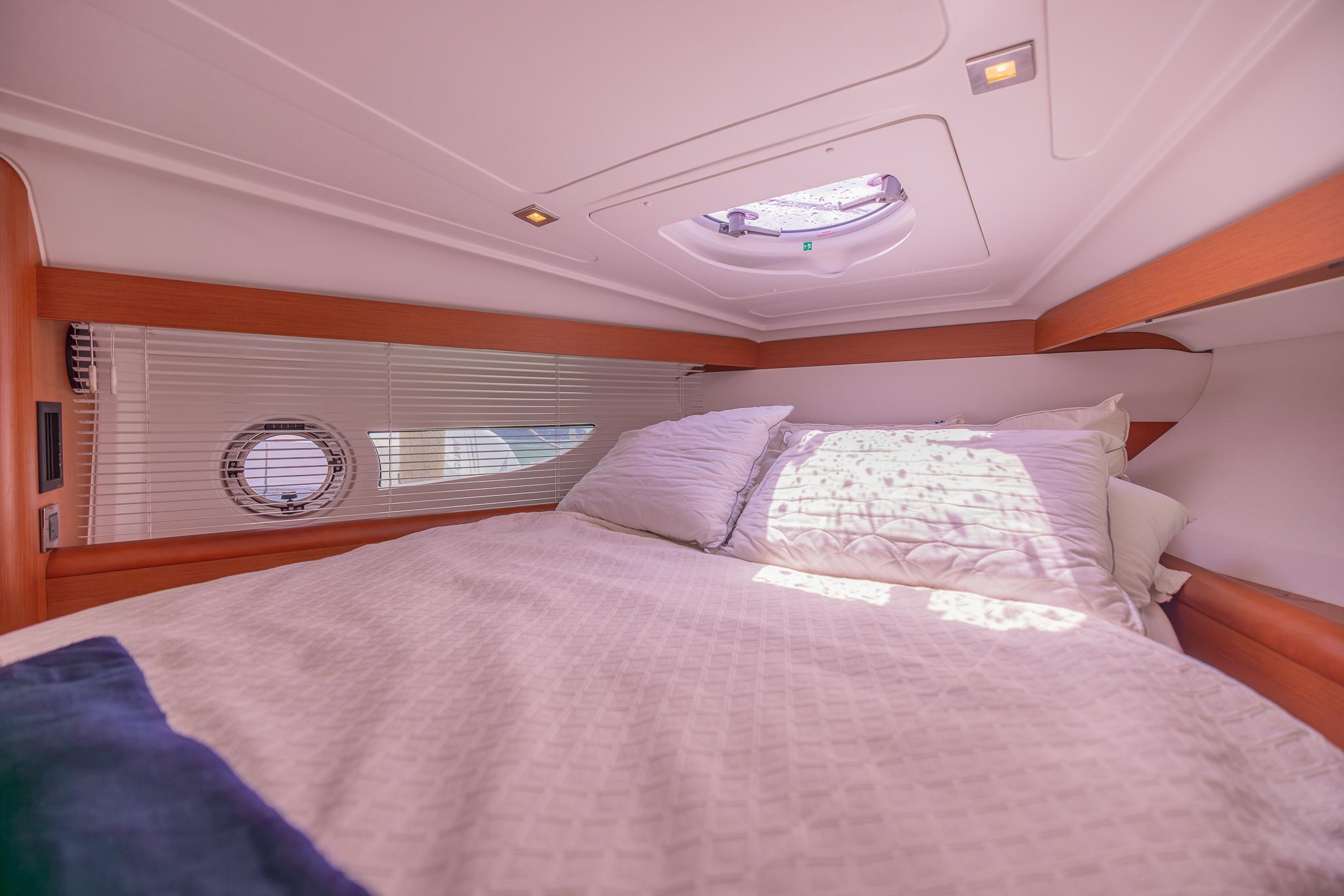 Cozy cabin interior of 2013 Beneteau Gran Turismo 38 yacht with bed and porthole.
