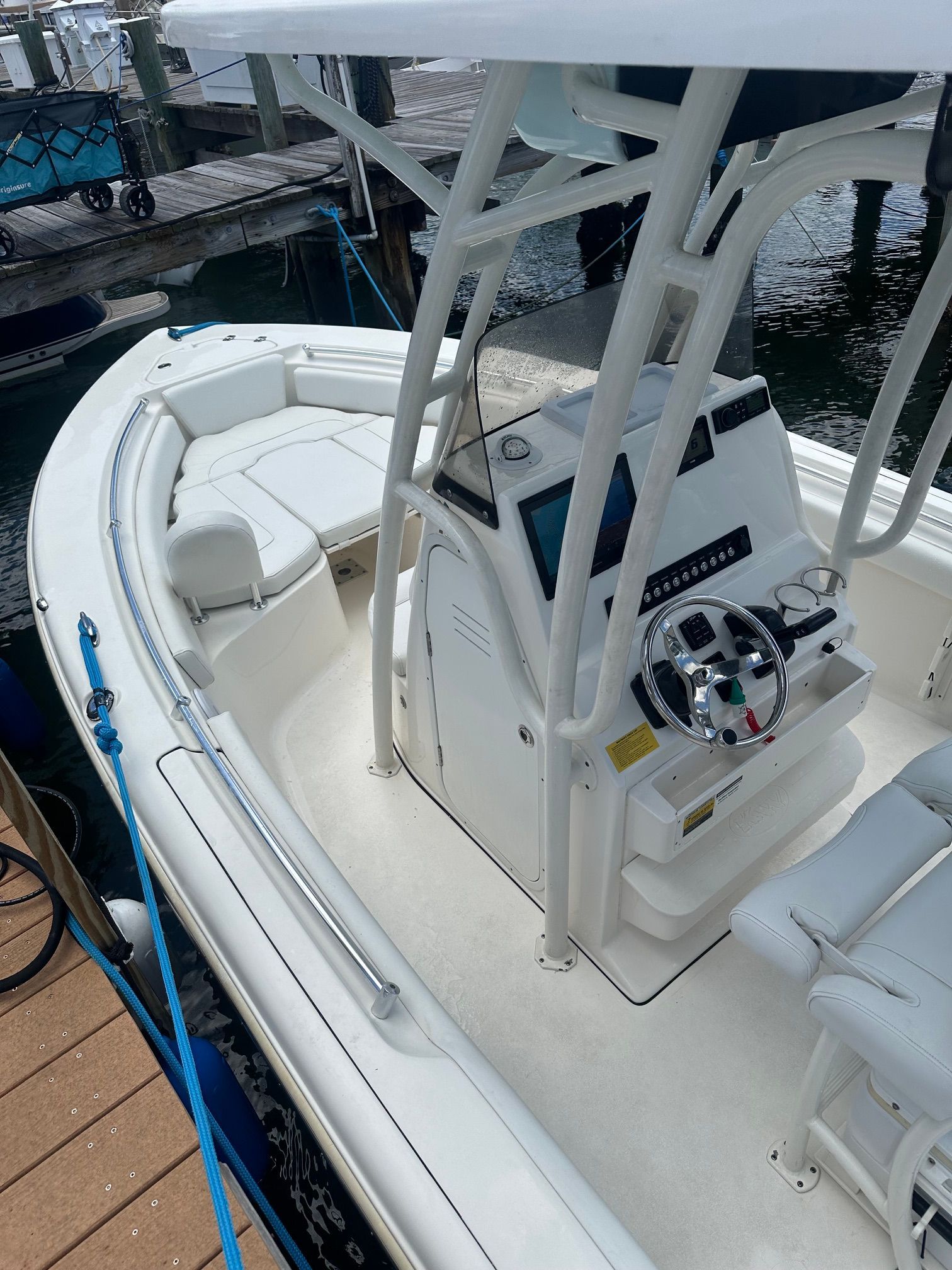 A modern motorboat with a helm and seating area, docked at a pier.
